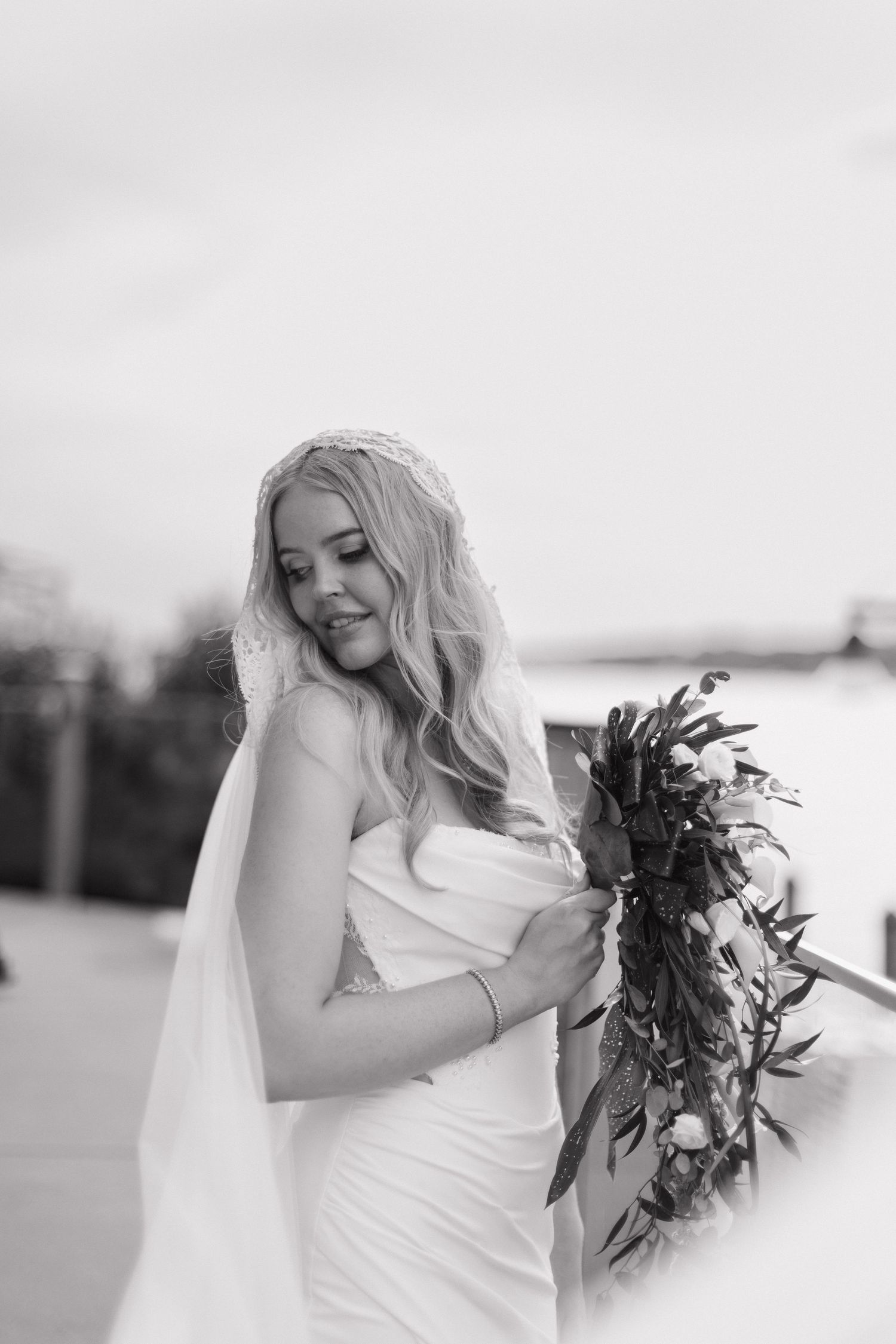 Black and white portrait series of a bride holding a dark bouquet against a light background.