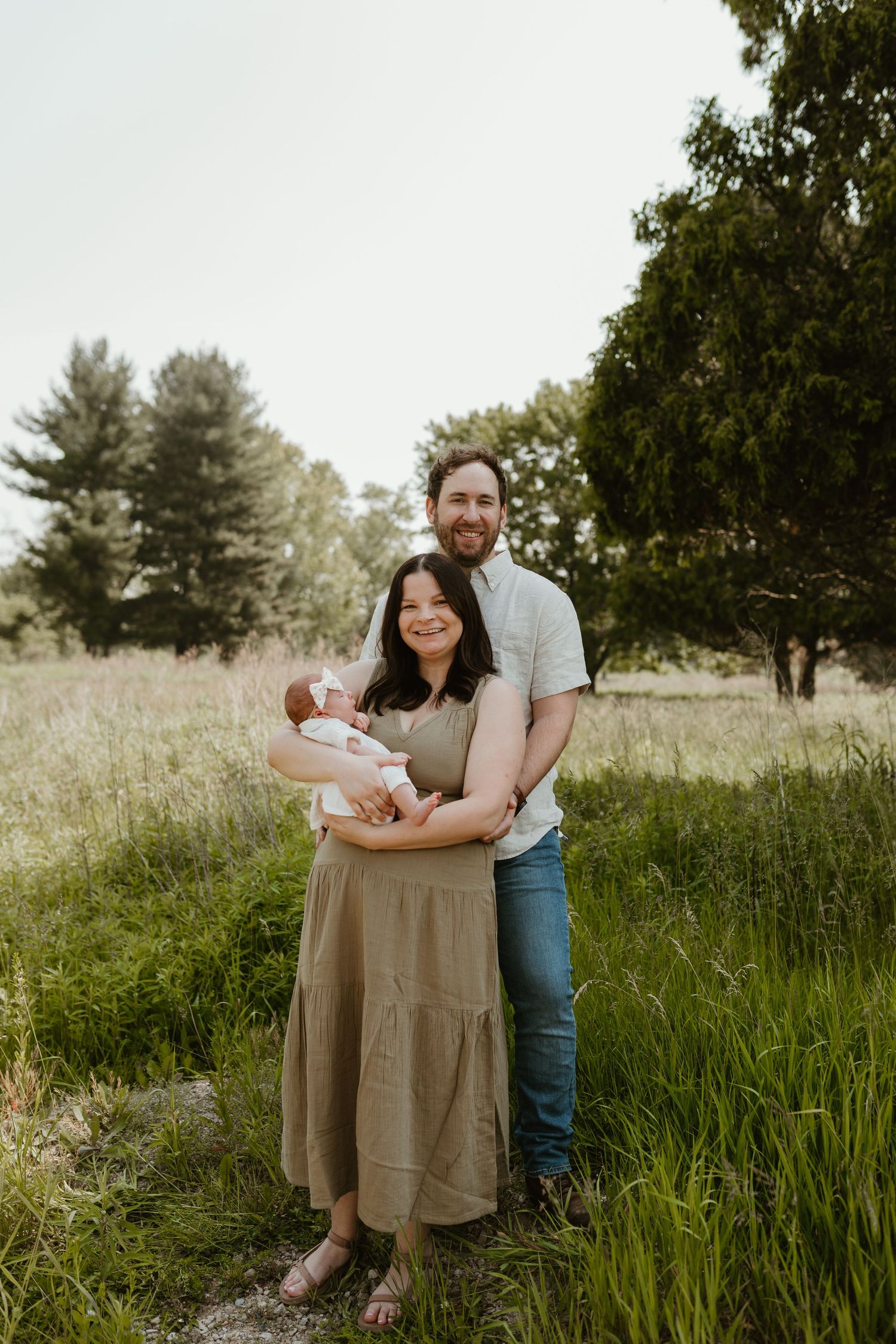 Family sitting together in a grassy field during a golden hour outdoor photo session.