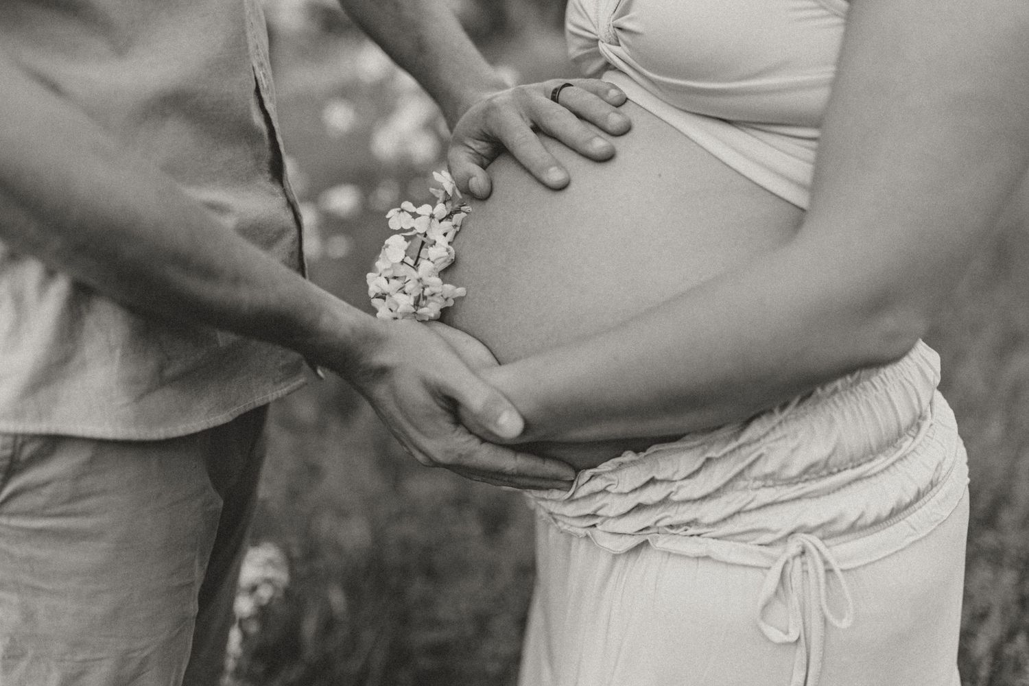 Intimate maternity photos showing gentle hands cradling a pregnant belly in soft lighting.