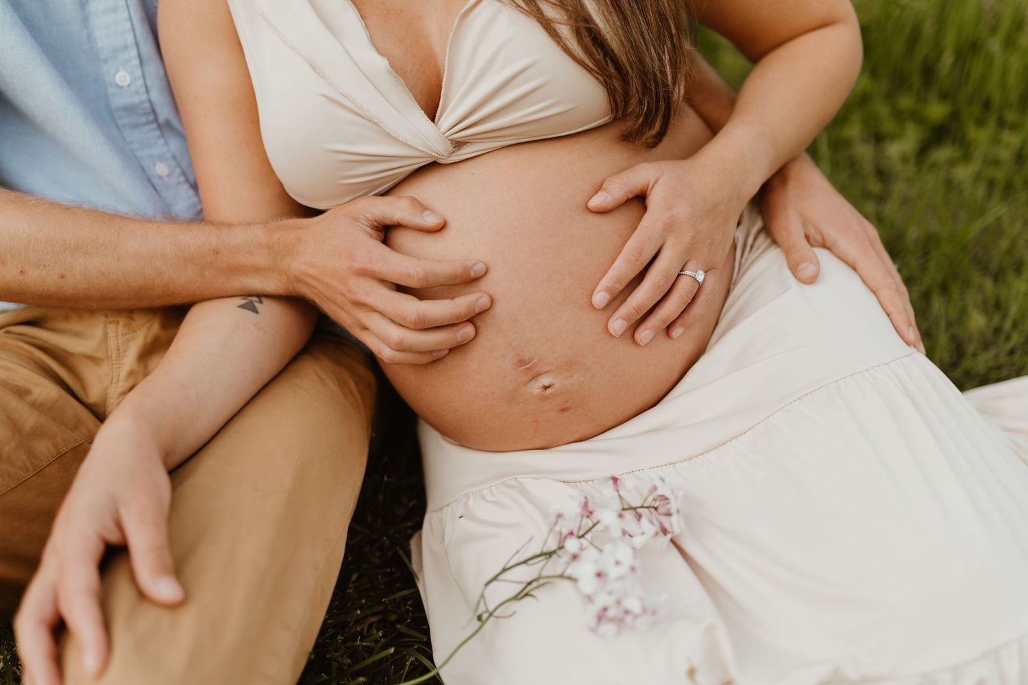 A maternity photo session captures intimate moments between expecting parents outdoors.