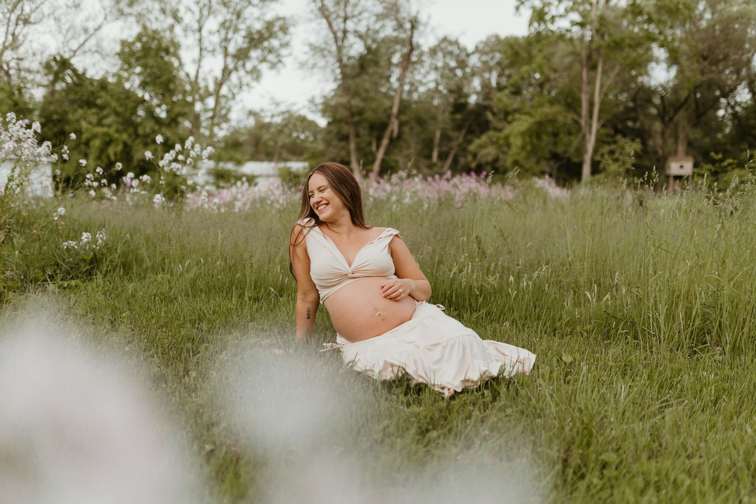 A maternity photo session in a wildflower field with soft, dreamy lighting.