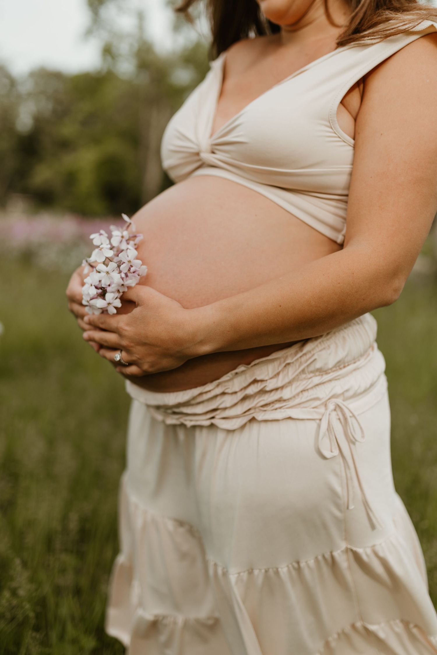 Close-up shots of a pregnant belly in a cream-colored dress against a natural outdoor backdrop.