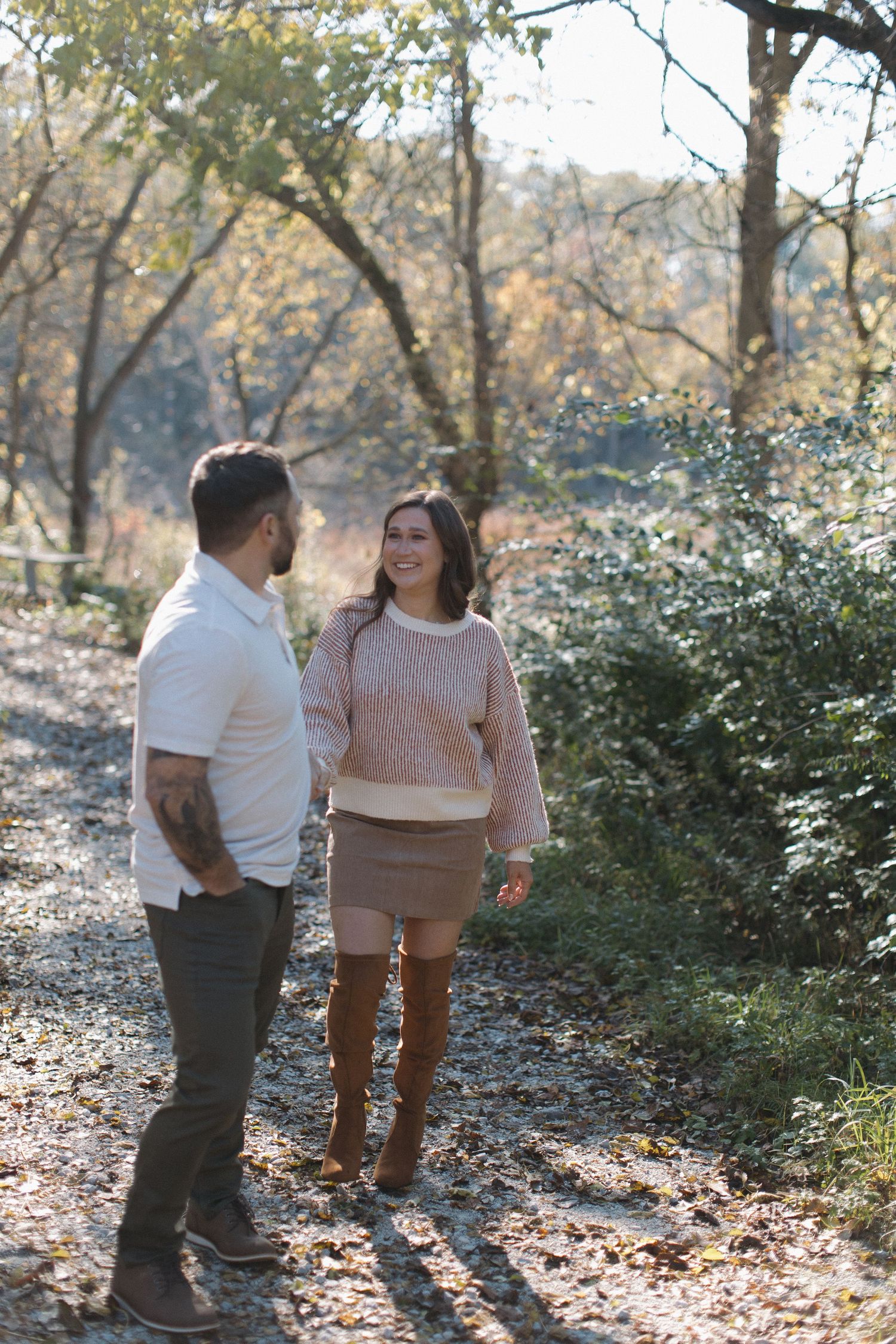 A couple enjoying a casual walk among autumn trees and bushes.