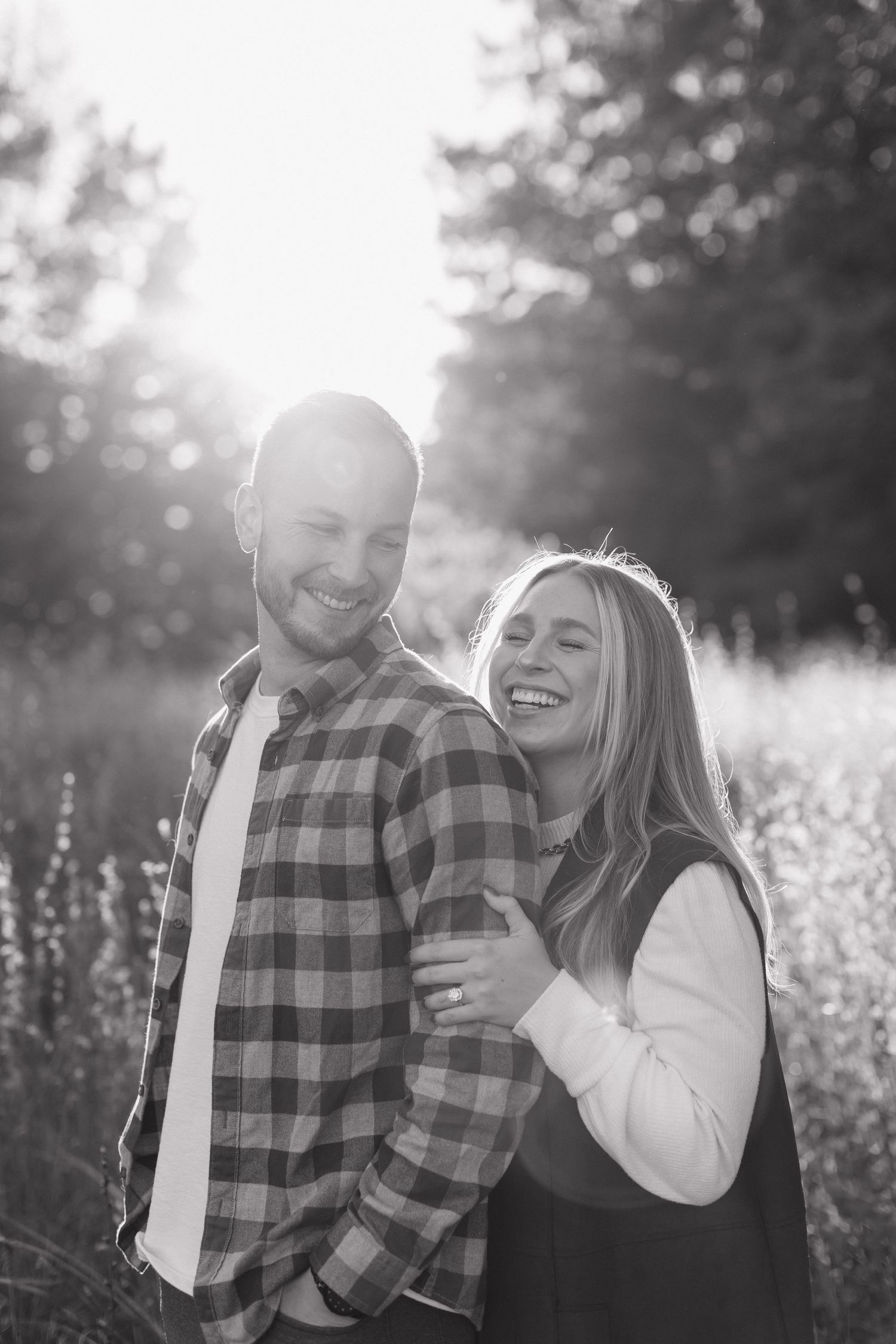 A joyful couple laughs together during their black and white outdoor photo session.