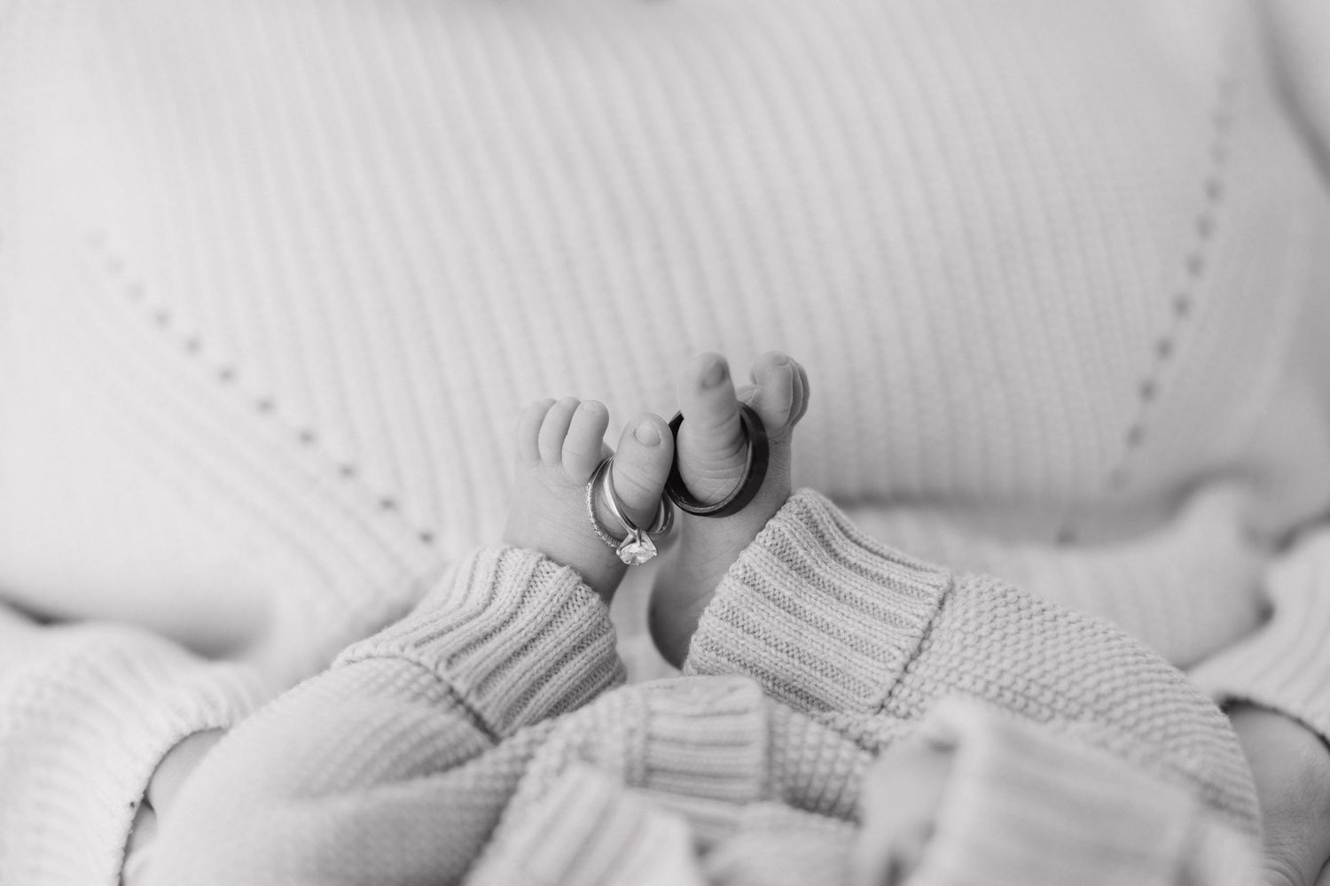 Soft focus detail of white knit baby clothing against a light background.