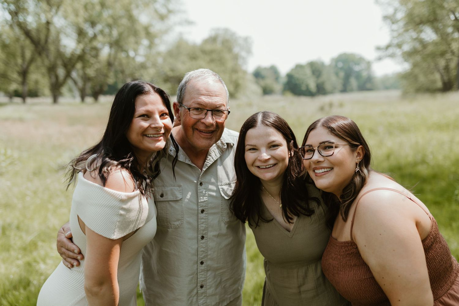 Group of people sharing warm embraces and laughter during an outdoor photo session.