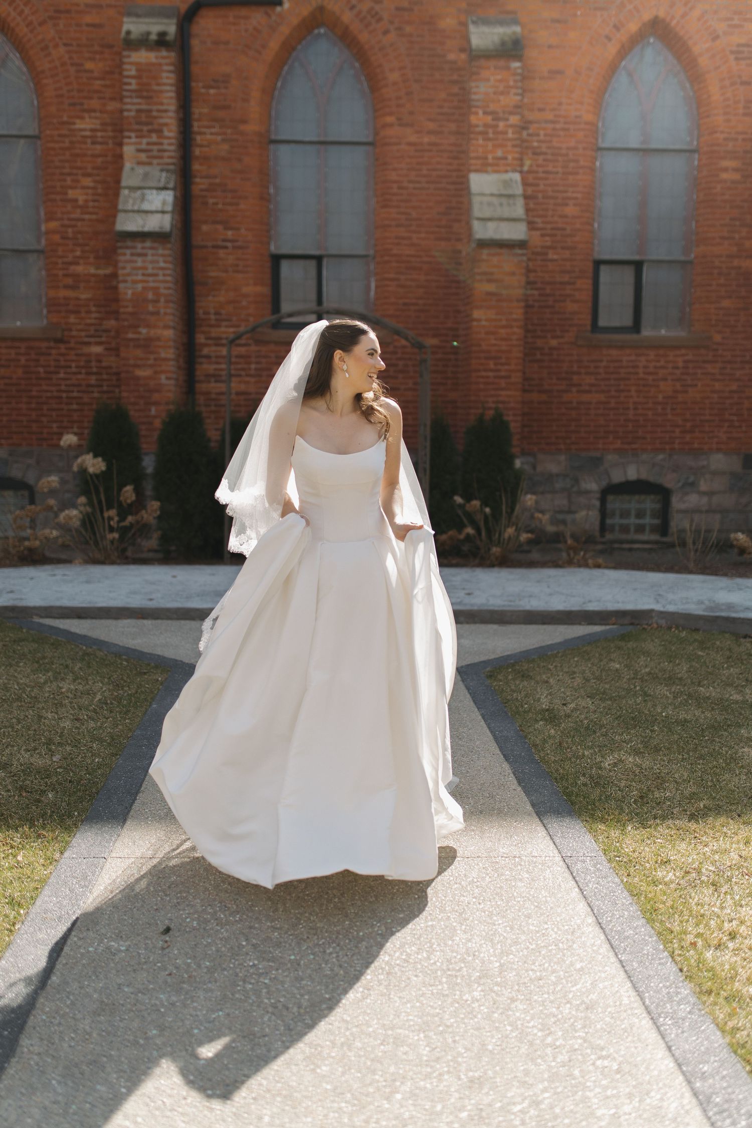 A flowing white wedding dress photographed in front of a historic red brick church.