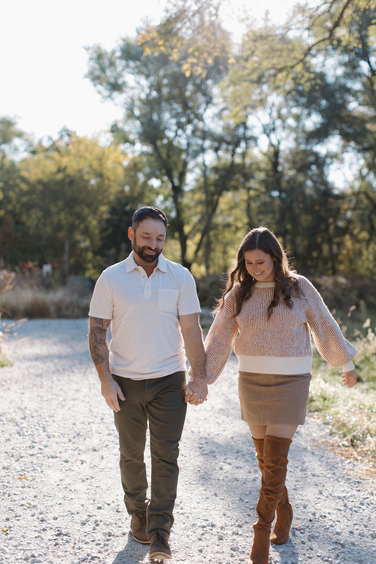 Candid engagement photos of a couple walking and laughing on a gravel path.