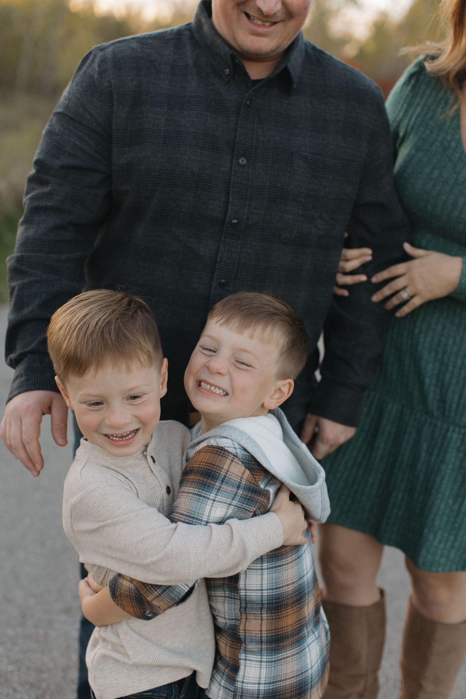 Children sharing joyful hugs and laughter during a casual outdoor photo session.