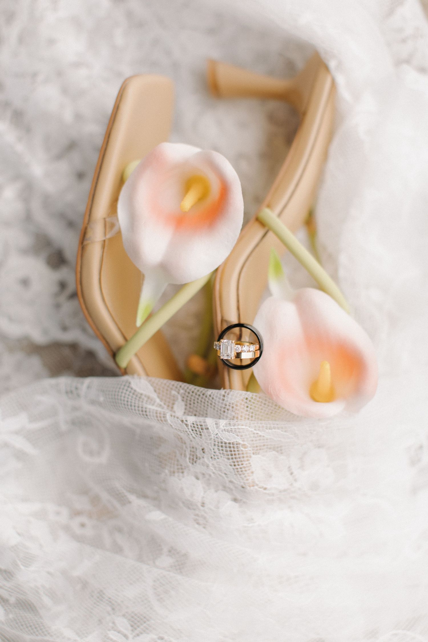 Delicate pink calla lilies nestled in soft white lace fabric with natural lighting.