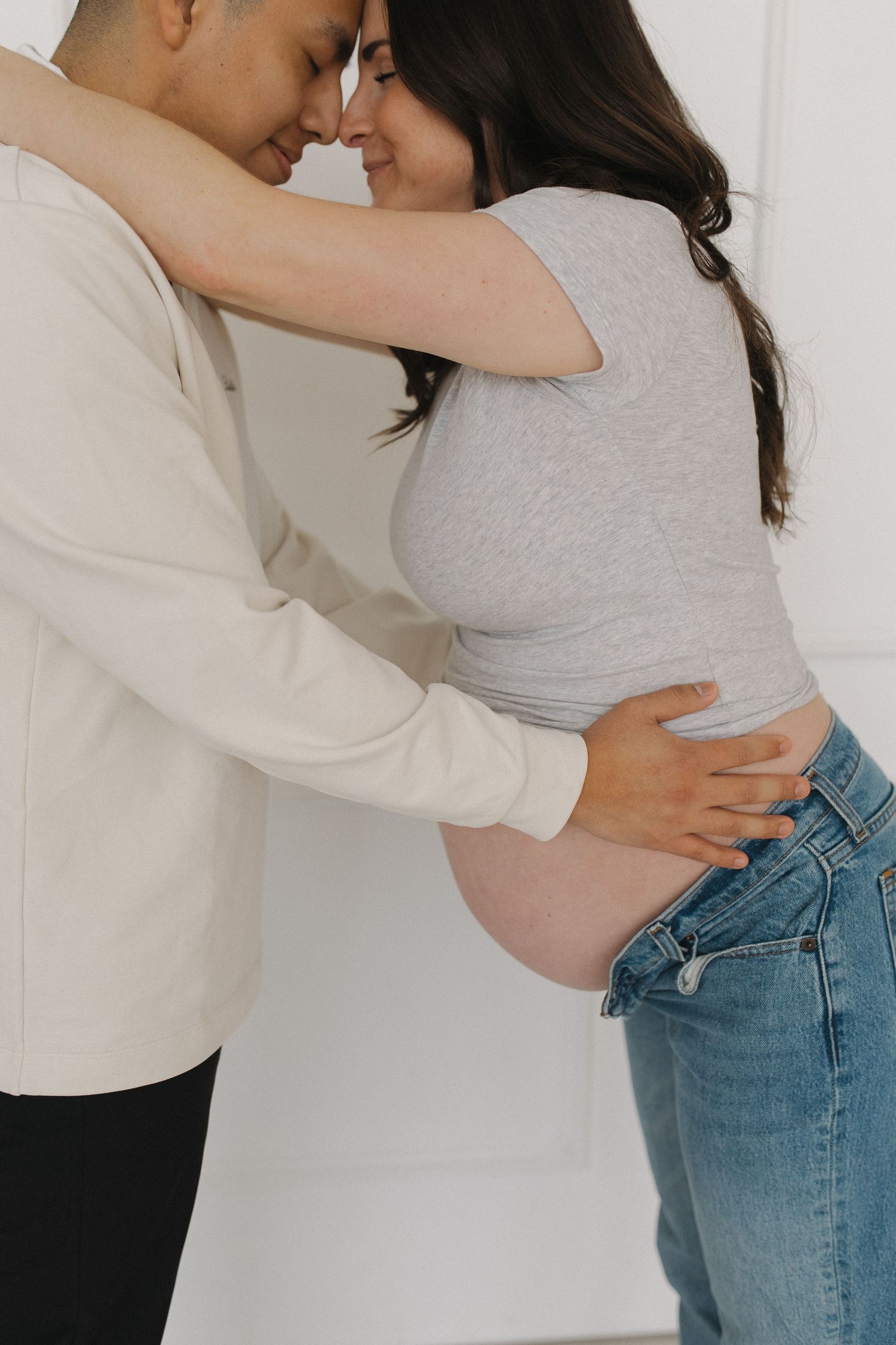 An intimate couple's portrait against a white wall showing tender moments.