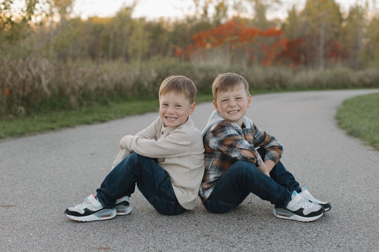 Close-up view of children's feet and legs sitting together on a paved path.