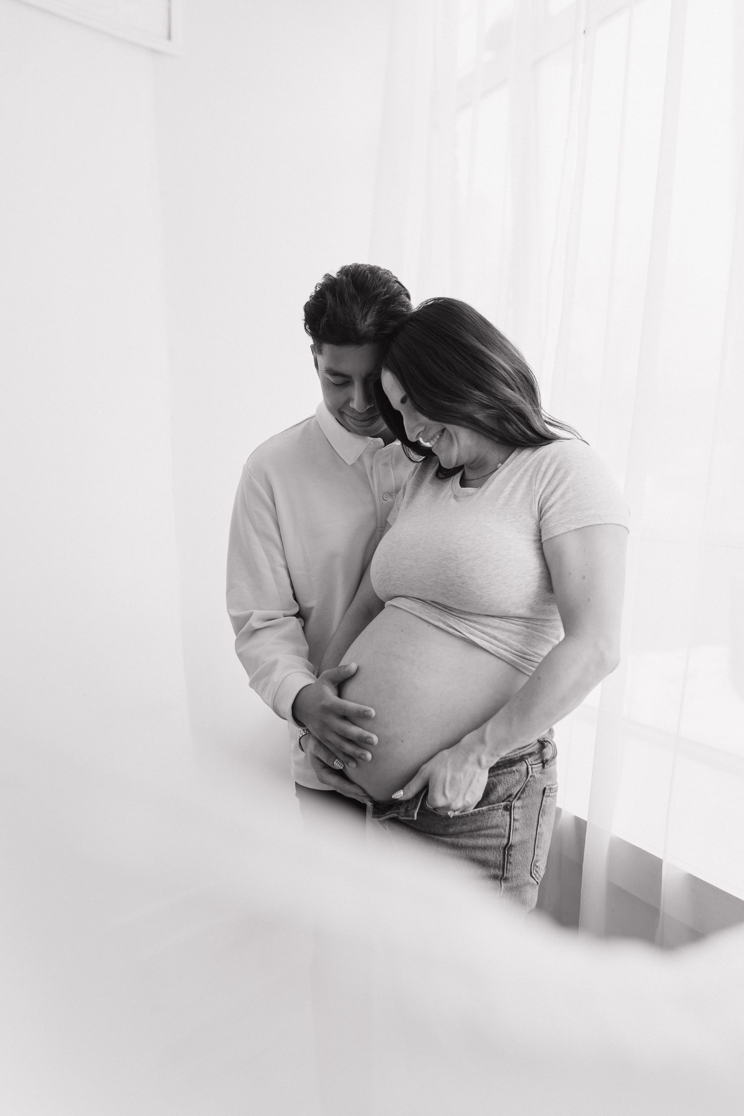 A black and white maternity photo showing a tender moment between a couple.
