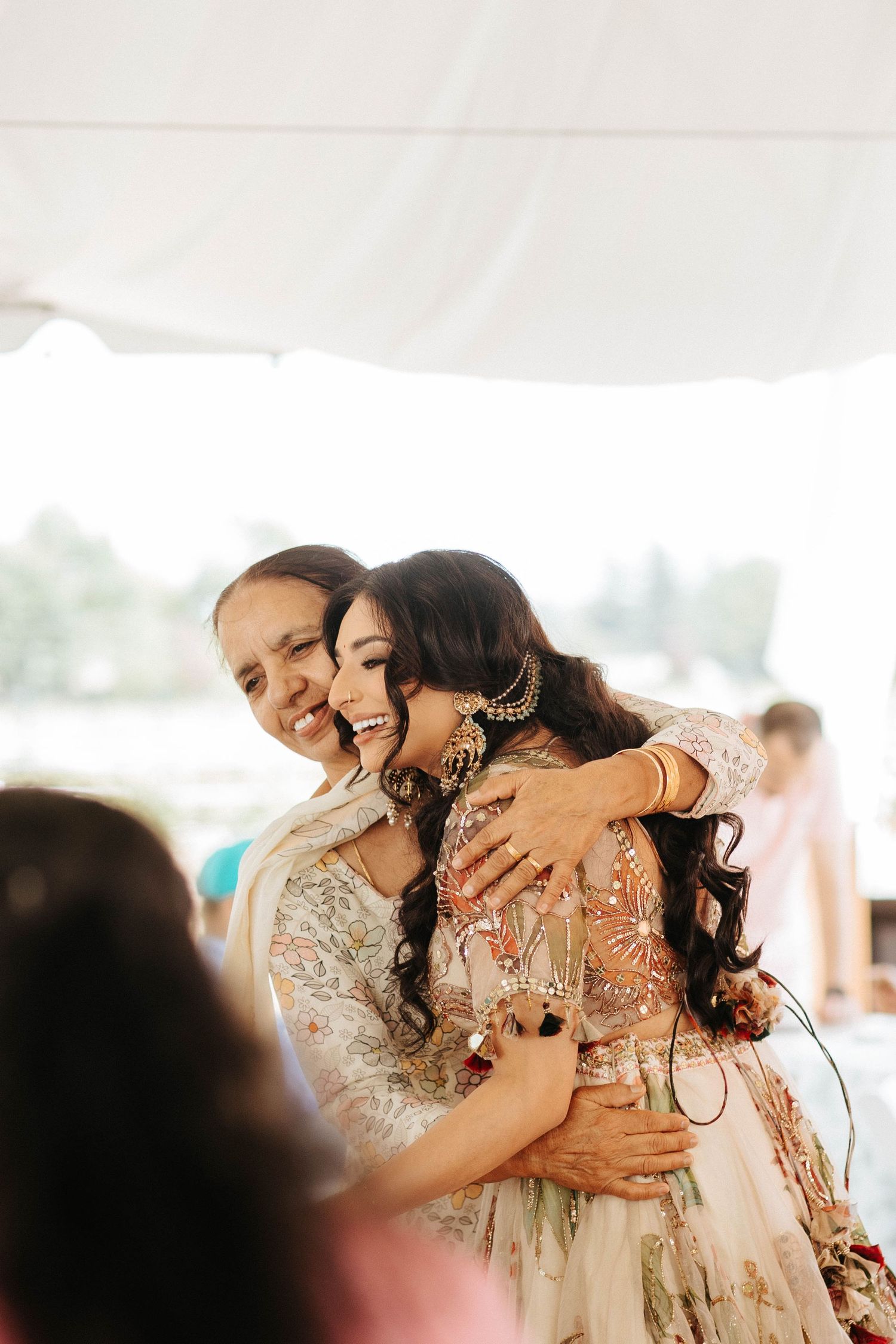 A joyful dancing couple embraces at a wedding reception under a white tent canopy.