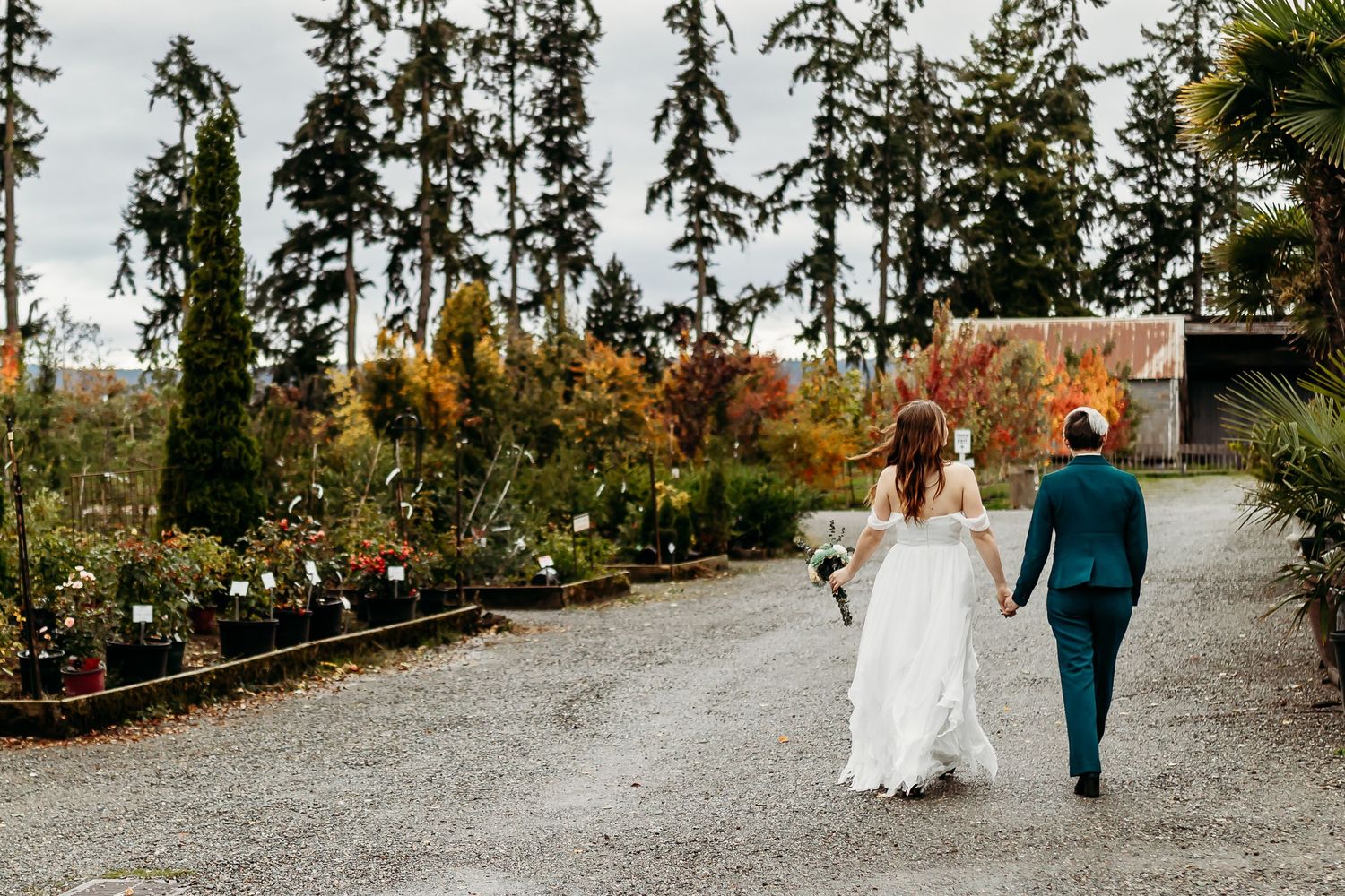 A couple walking down a garden path surrounded by autumn foliage and potted plants.