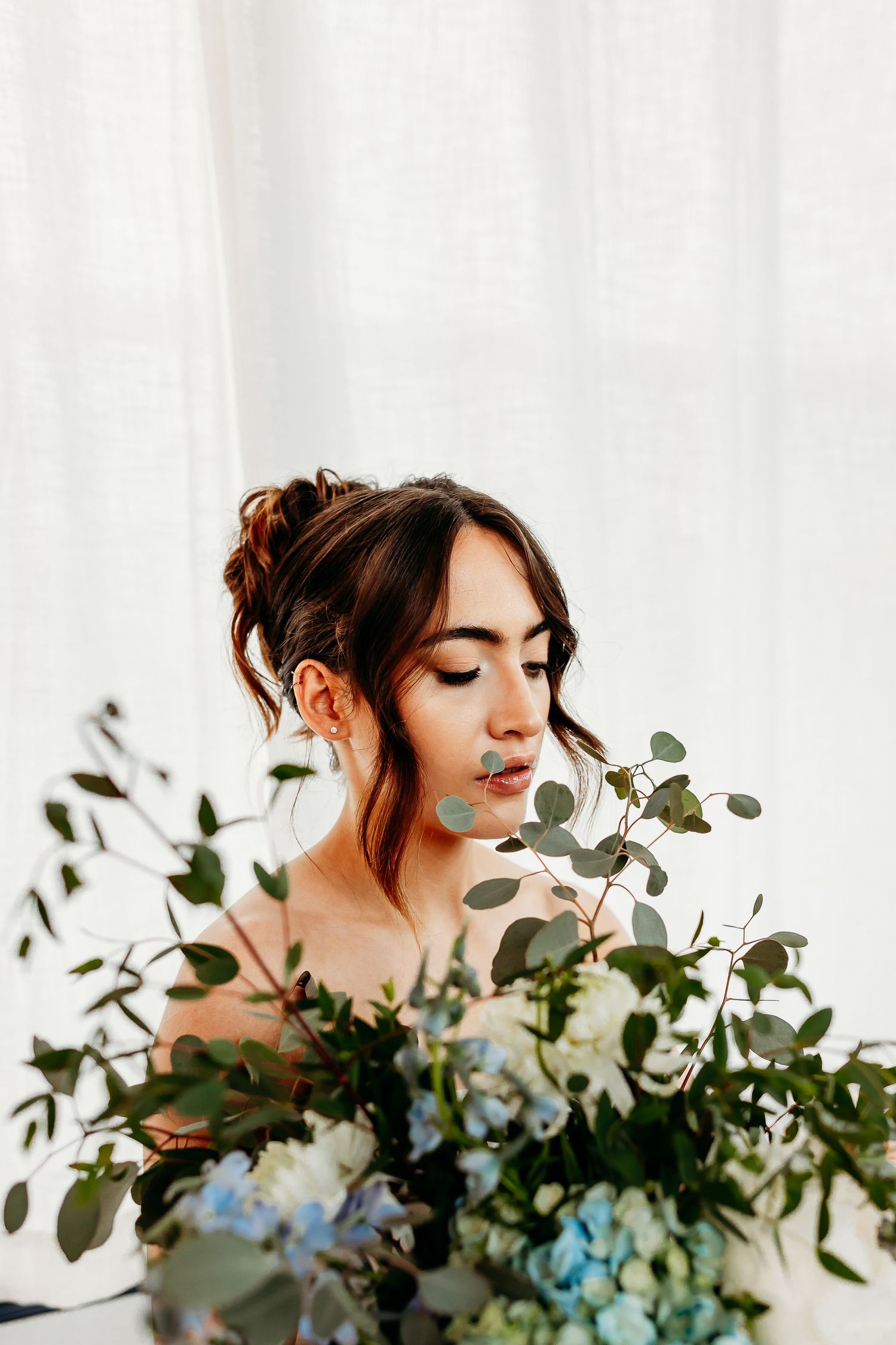 An artistic portrait with eucalyptus and blue floral bouquet details.