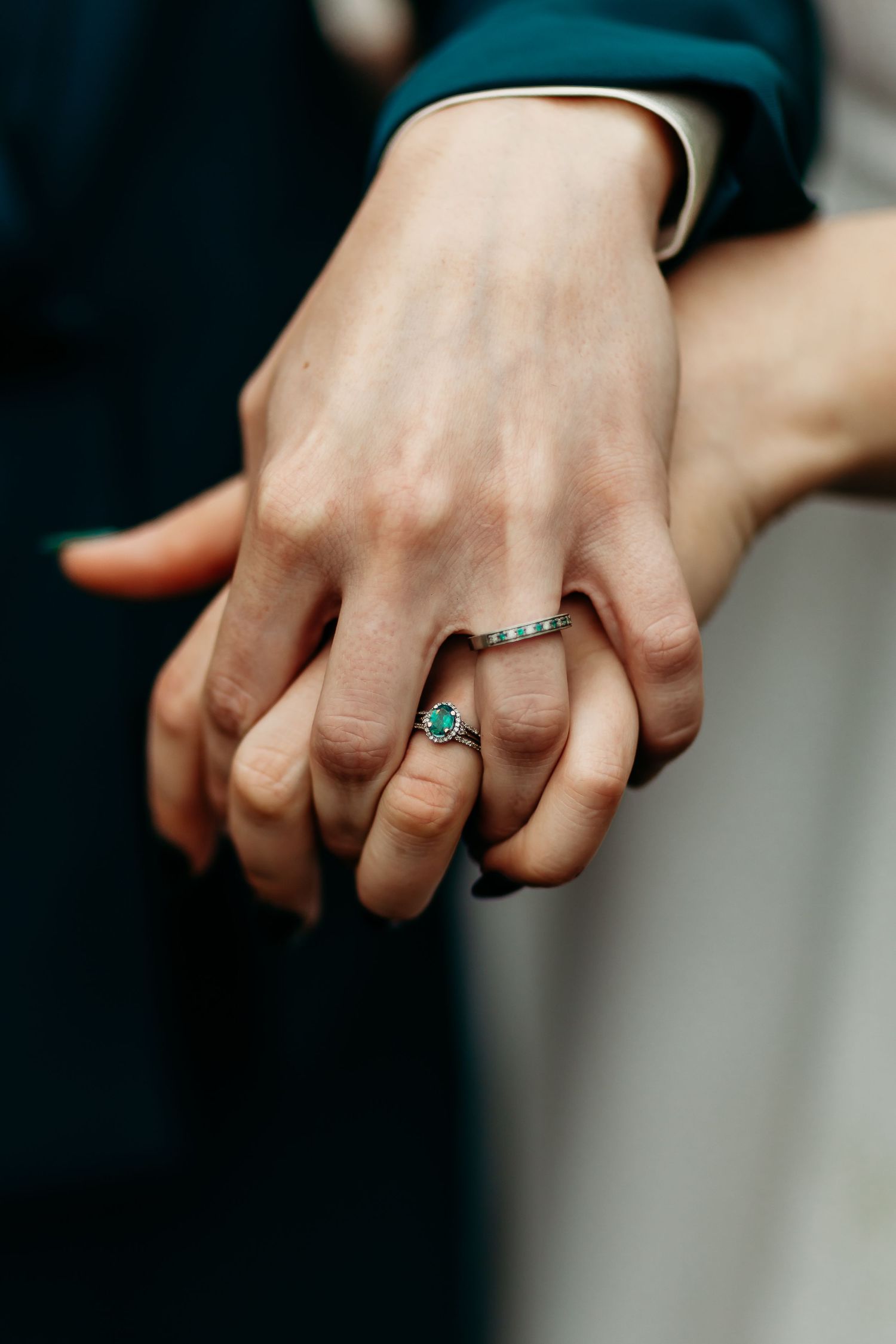 Close-up of clasped hands showing turquoise engagement ring and wedding band.