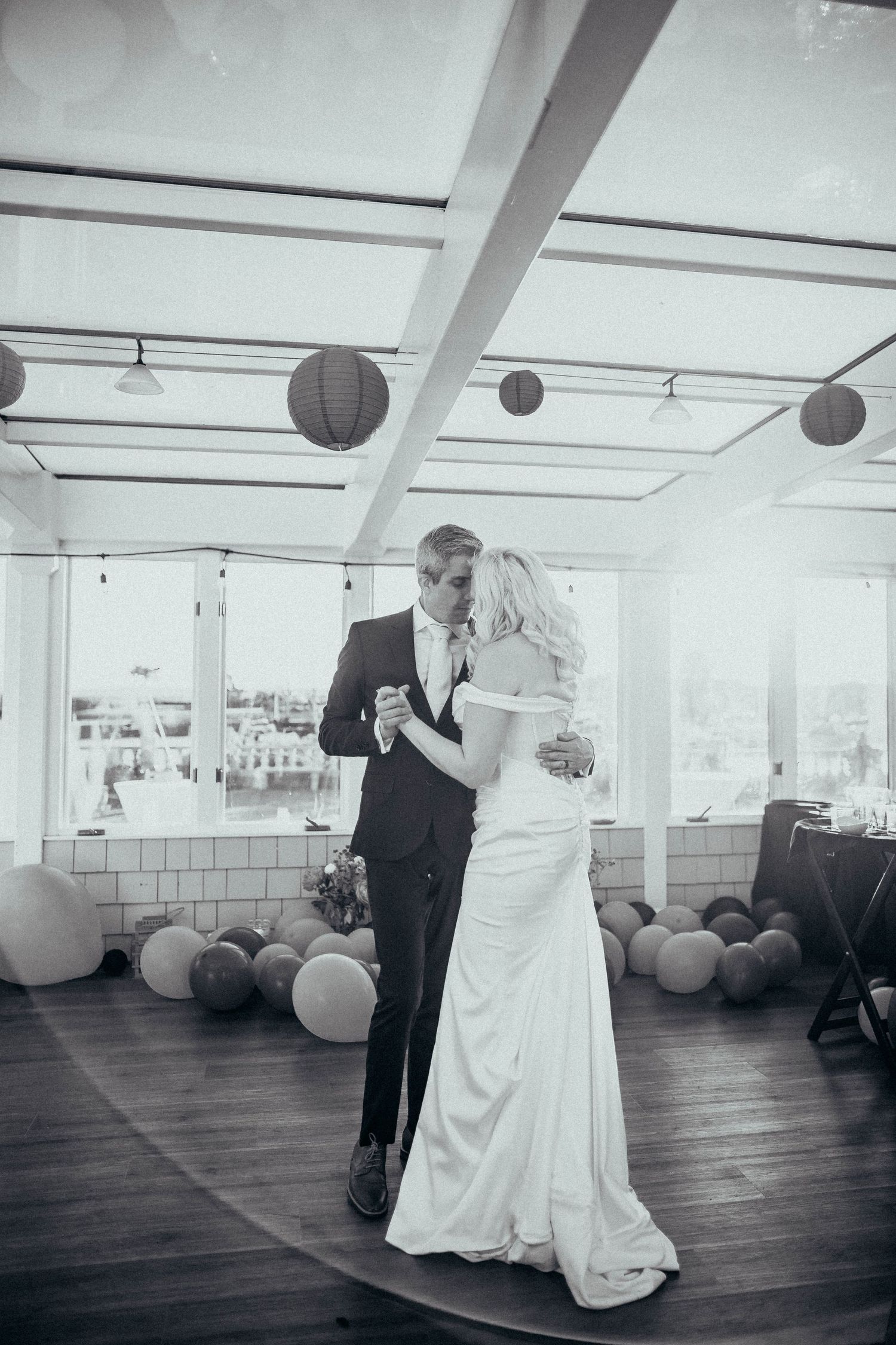 Newlyweds share an intimate first dance in an elegant venue decorated with balloons and lanterns.