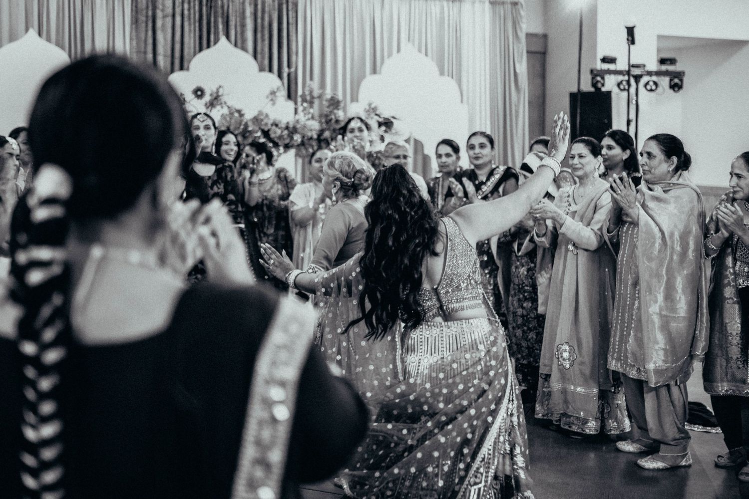 Black and white photo of wedding guests dancing and celebrating during a lively dance party at a reception.
