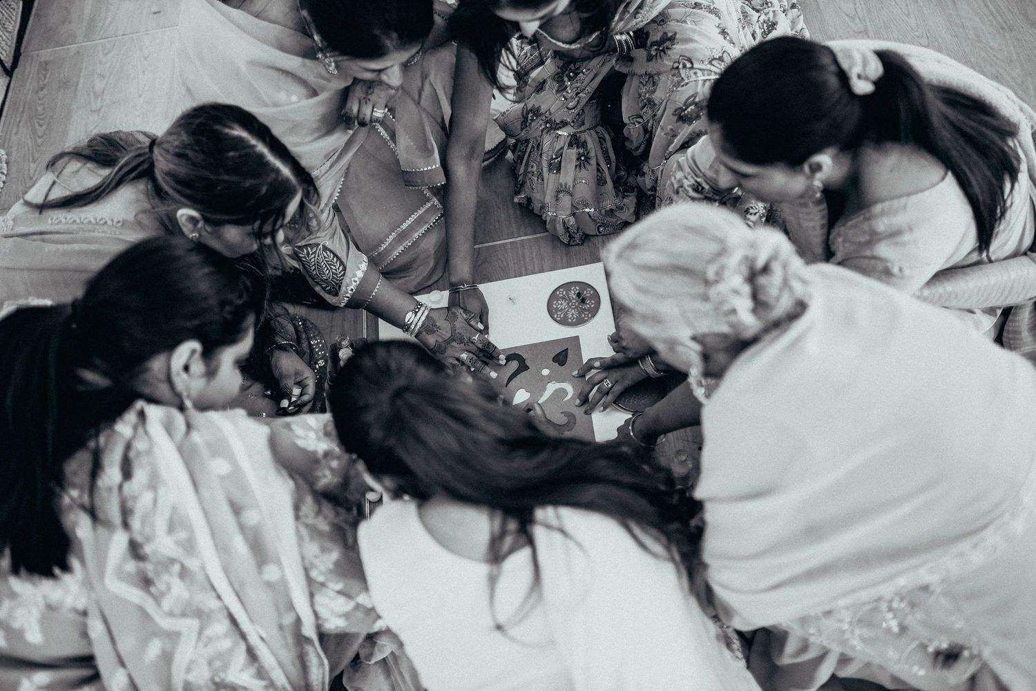A black and white overhead view of people gathered on the floor looking at something together.