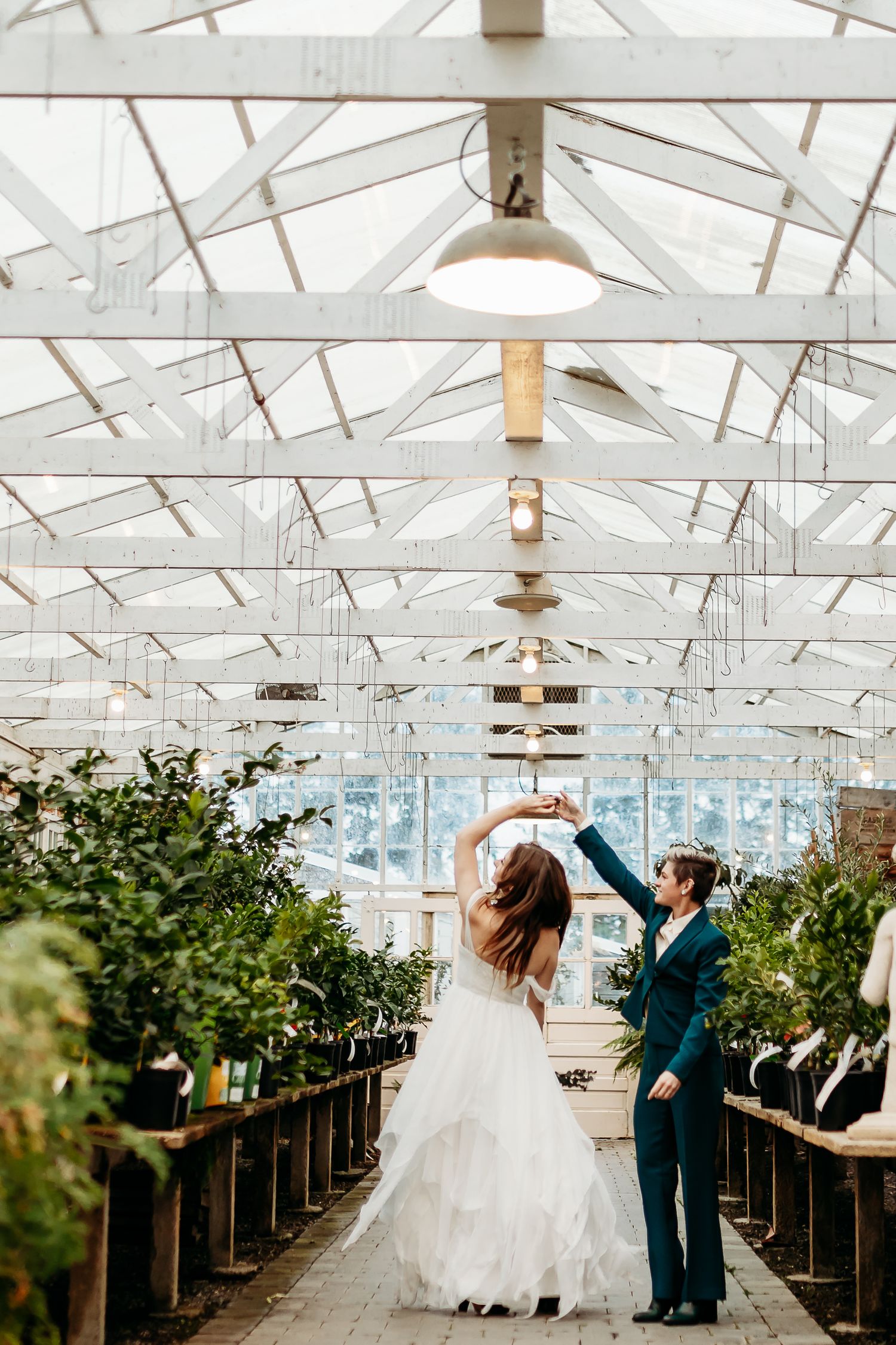 A romantic dance in a sunlit greenhouse filled with plants and white architectural details.
