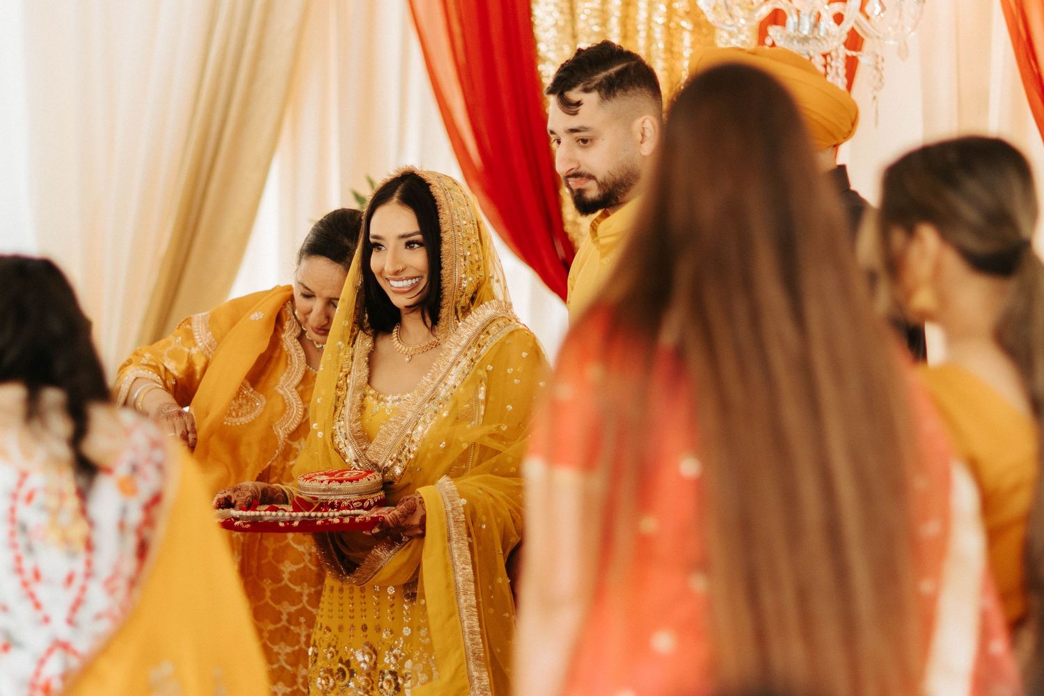 Traditional Indian wedding ceremony with red and gold decor during an indoor celebration.