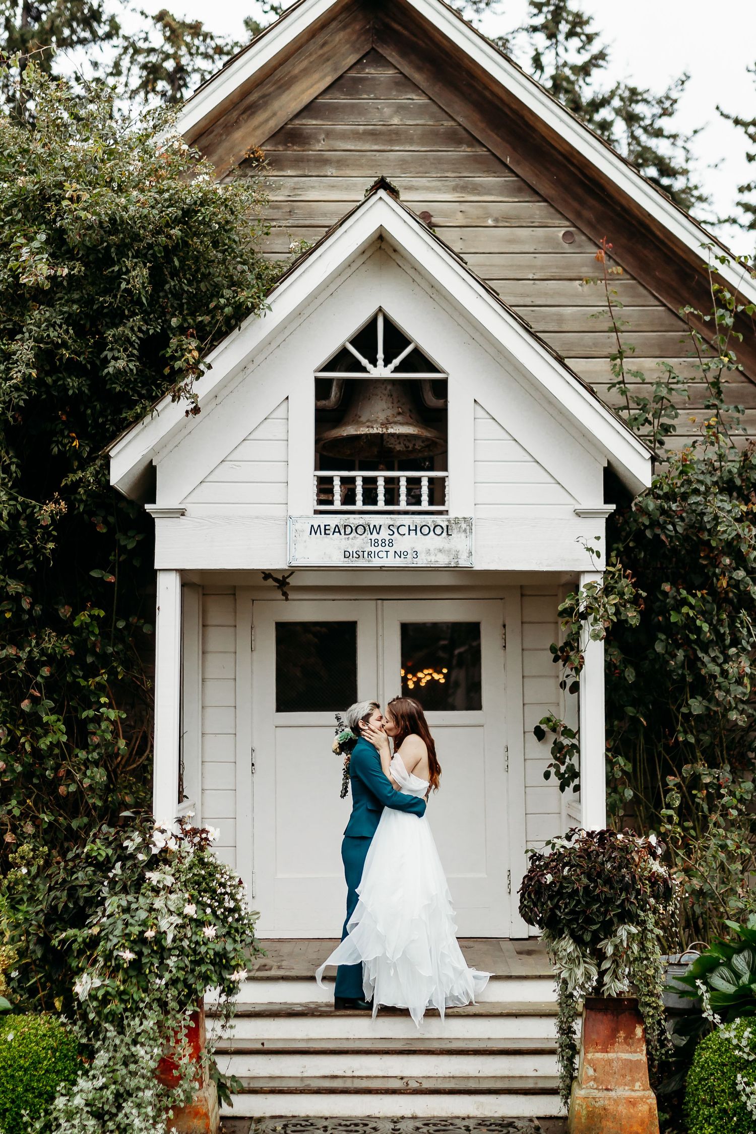 Romantic wedding portrait in front of charming white chapel with wooden details.