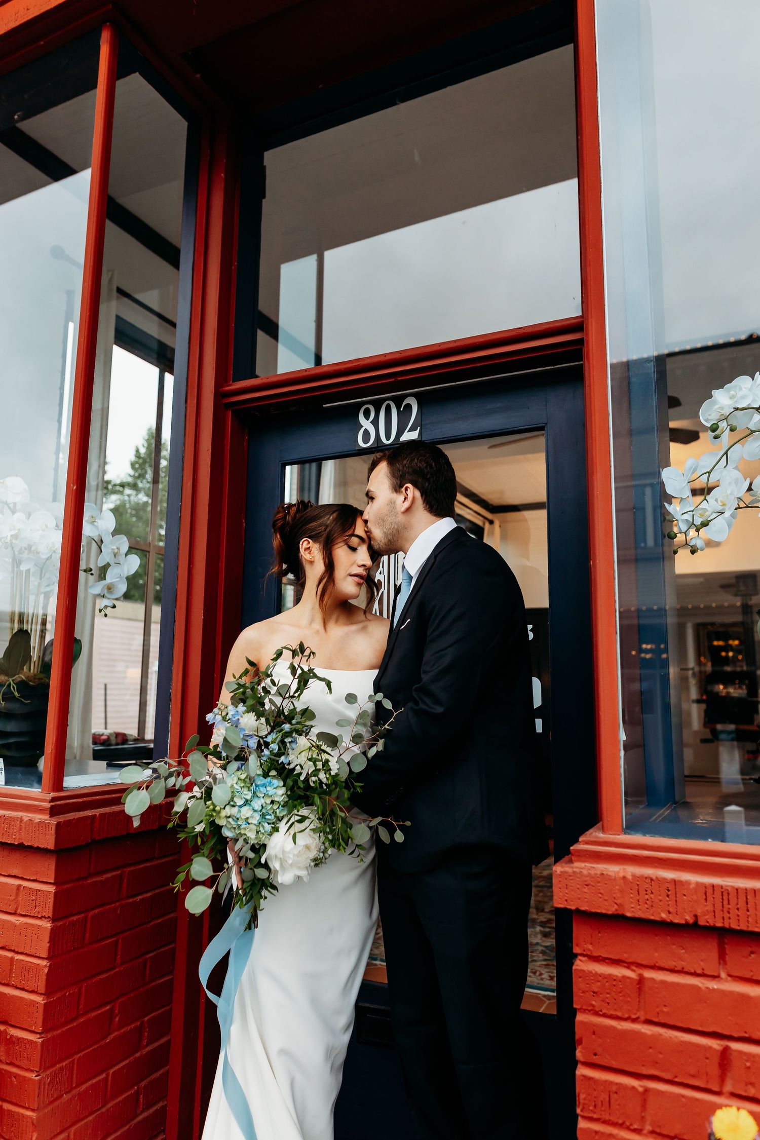 A romantic moment captured in a doorway of a red brick building numbered 802.