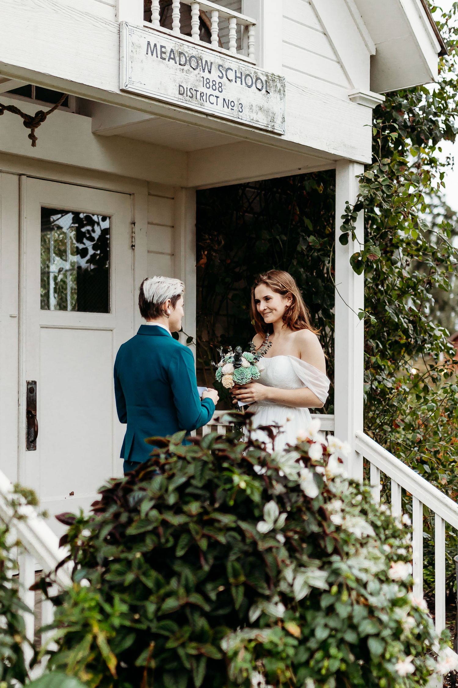 Wedding ceremony at historic Meadow School with couple on white porch steps.