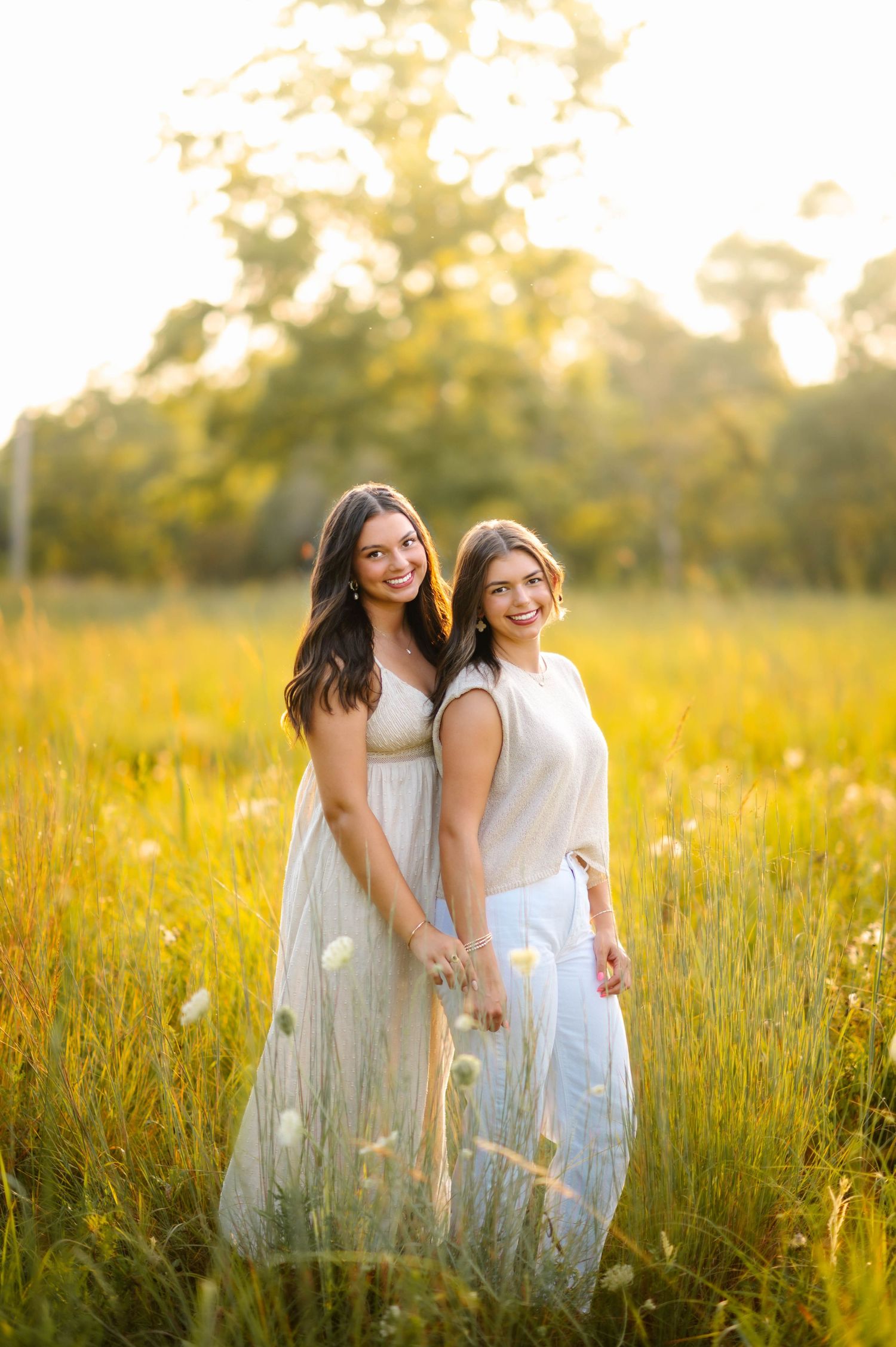 Two people share laughs while standing in a sunlit meadow with wildflowers.