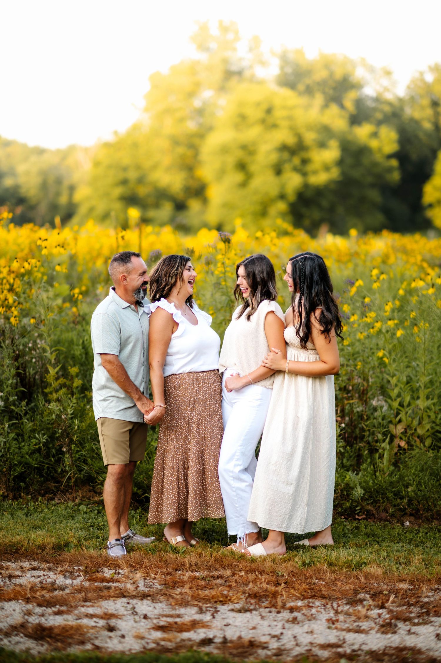 Family group poses together in a field of yellow wildflowers during golden hour.