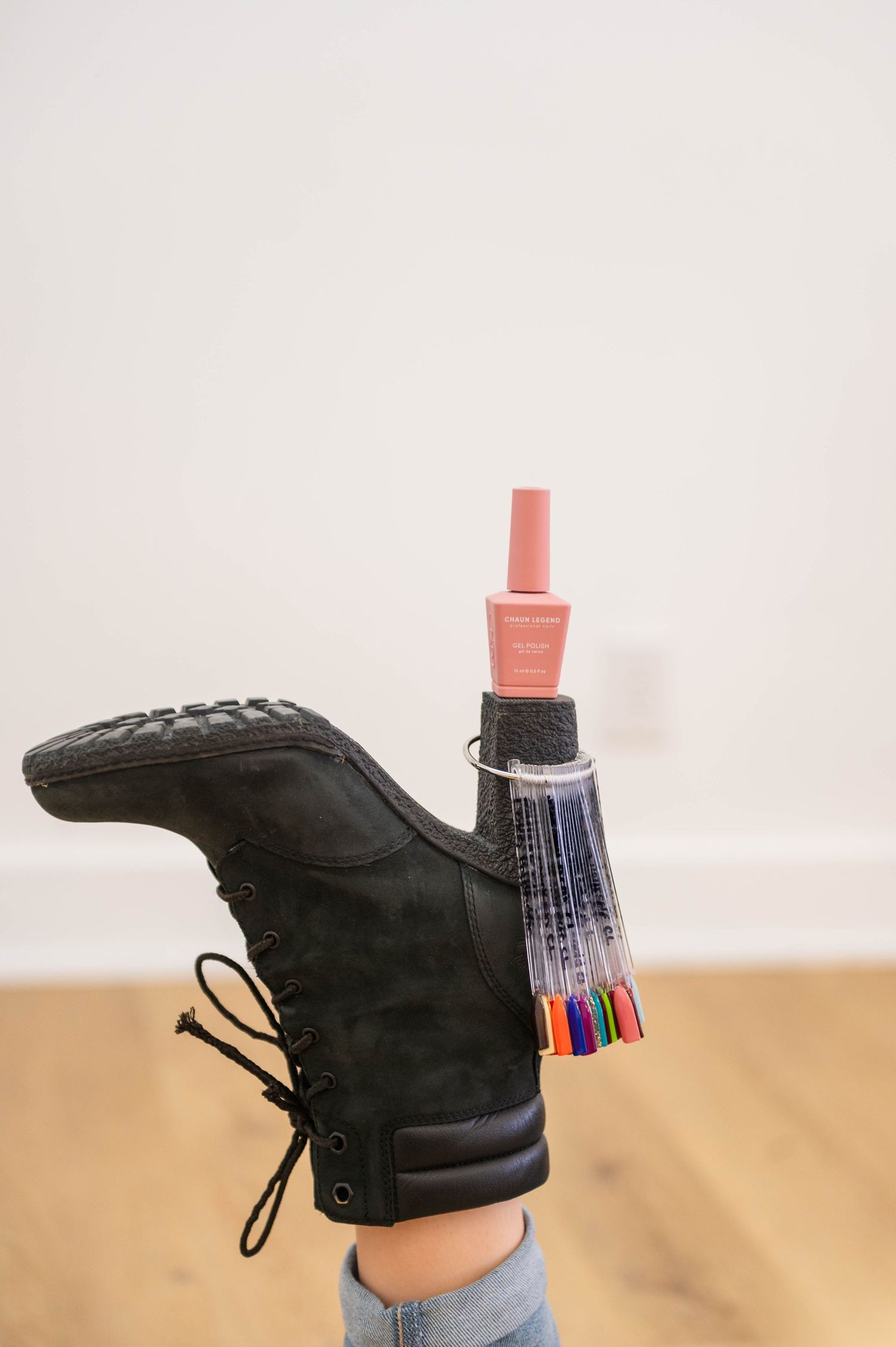 Black combat boots with nail polish bottles balanced on top against white background.