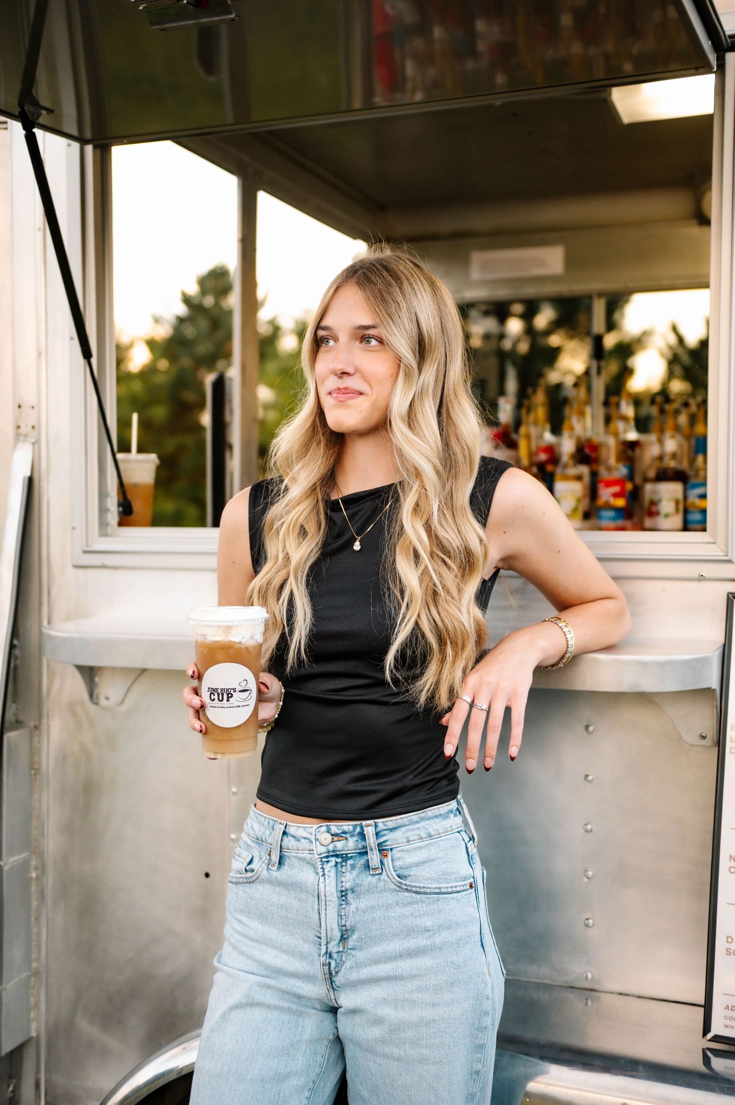 Woman serving drinks from June Bug's Cup mobile coffee truck window.