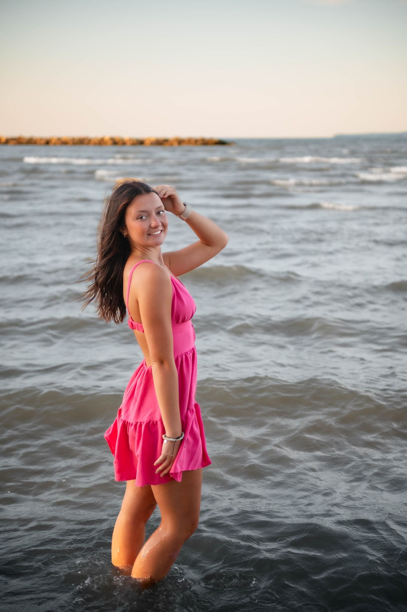 Person in pink swimsuit poses playfully in ocean waves.
