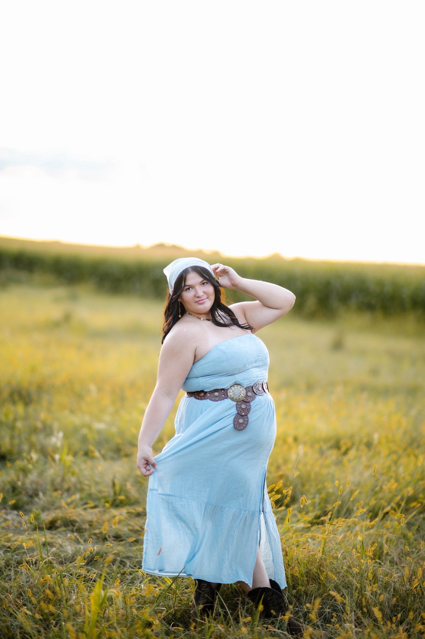 Person in light blue dress poses gracefully in summer meadow.