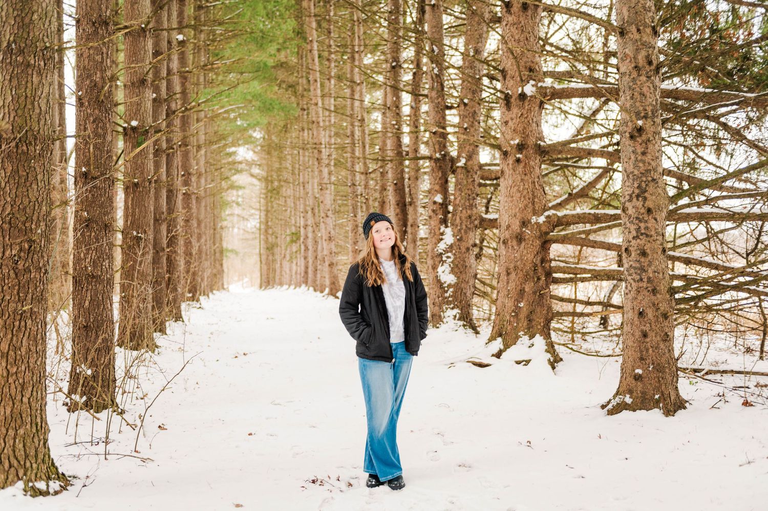 Friends enjoying a winter photoshoot in a snowy pine forest setting.
