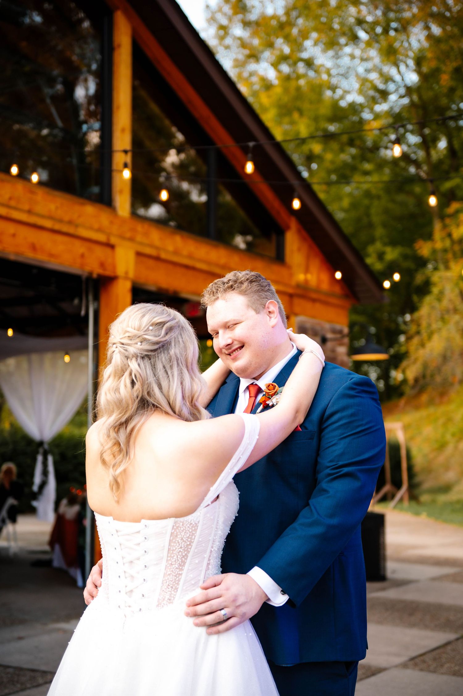 Couple embraces during their wedding day at a rustic outdoor venue.