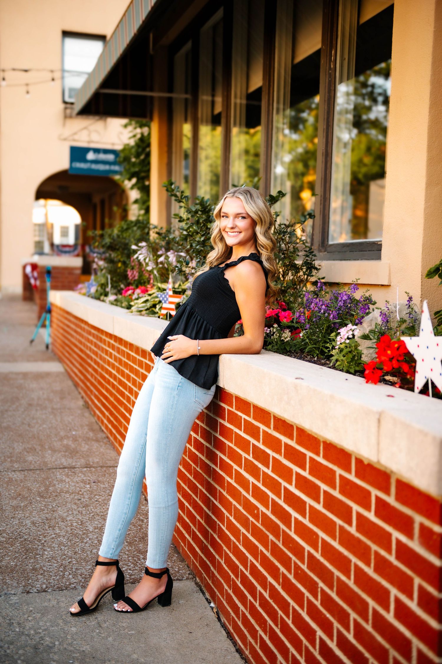 Casual portrait session against brick storefront with colorful flower planters.