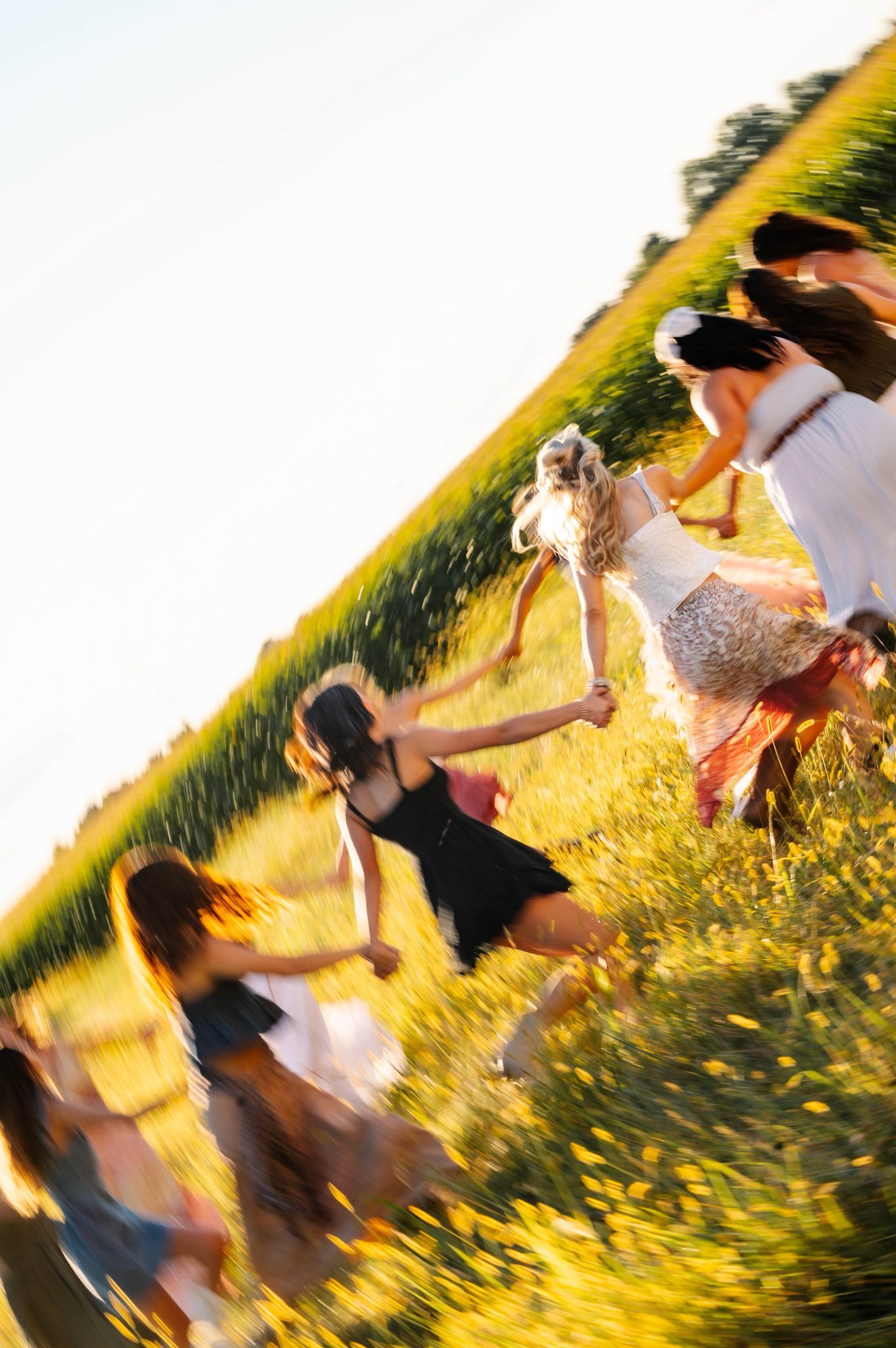 Motion-blurred photo of friends spinning in a circle during golden hour.