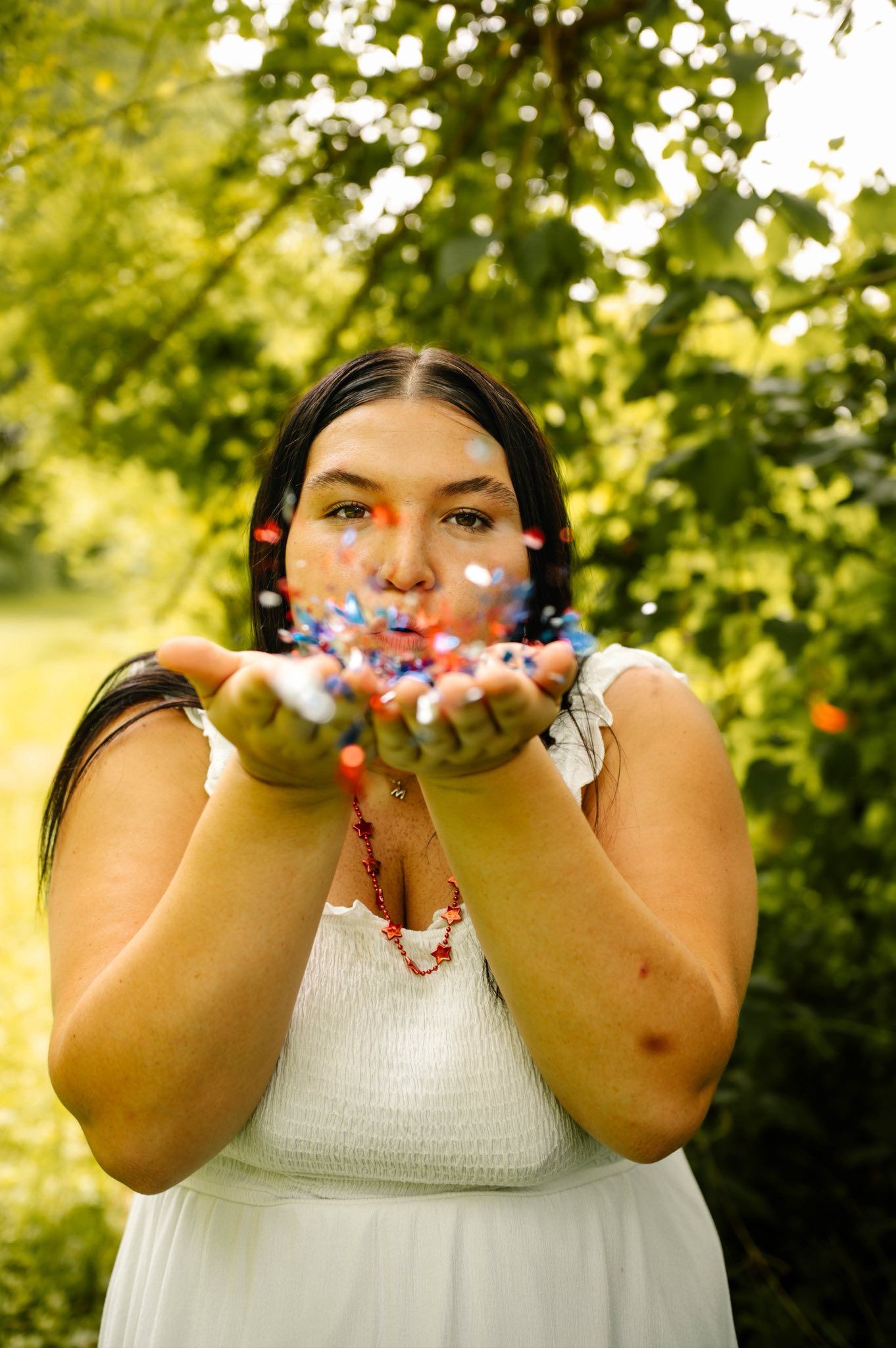 Red and white confetti being blown against a green summer background in a celebratory moment.