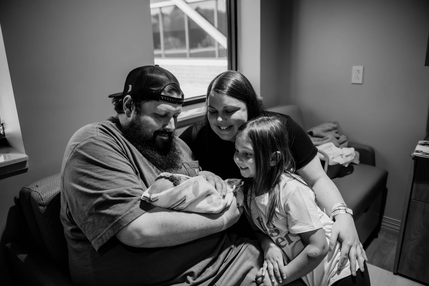 Family shares an intimate moment together while visiting a newborn in the hospital.