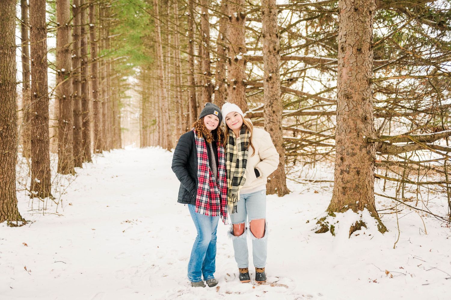 Winter forest photoshoot with friends walking through snow-covered pine trees.