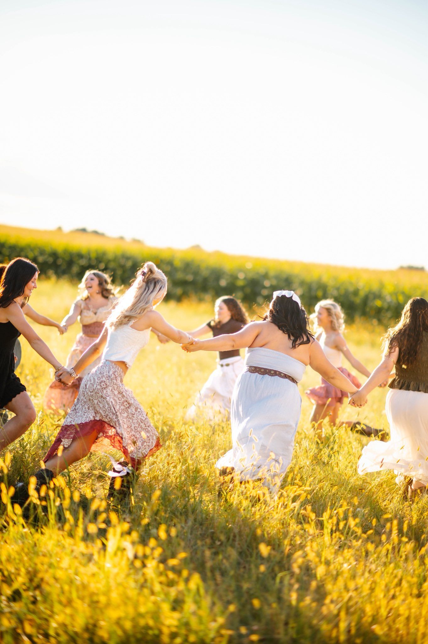 Group dancing joyfully in a sunlit meadow filled with wildflowers during golden hour.