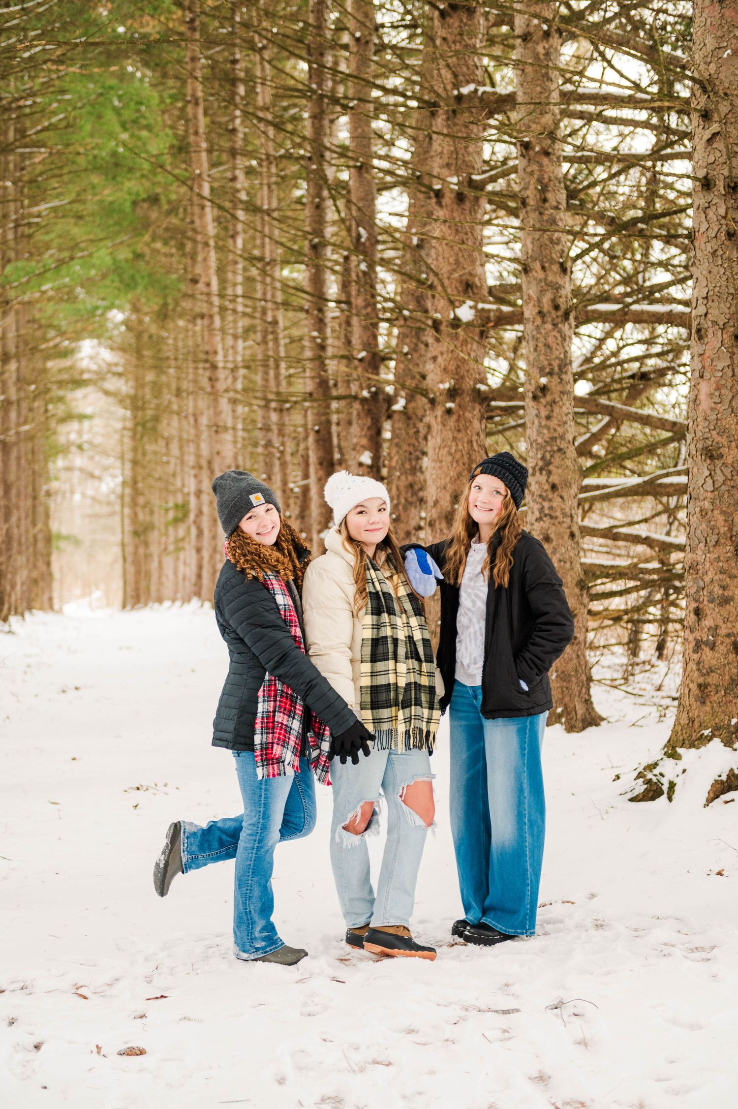 People standing together in a snowy forest wearing winter jackets and casual attire.