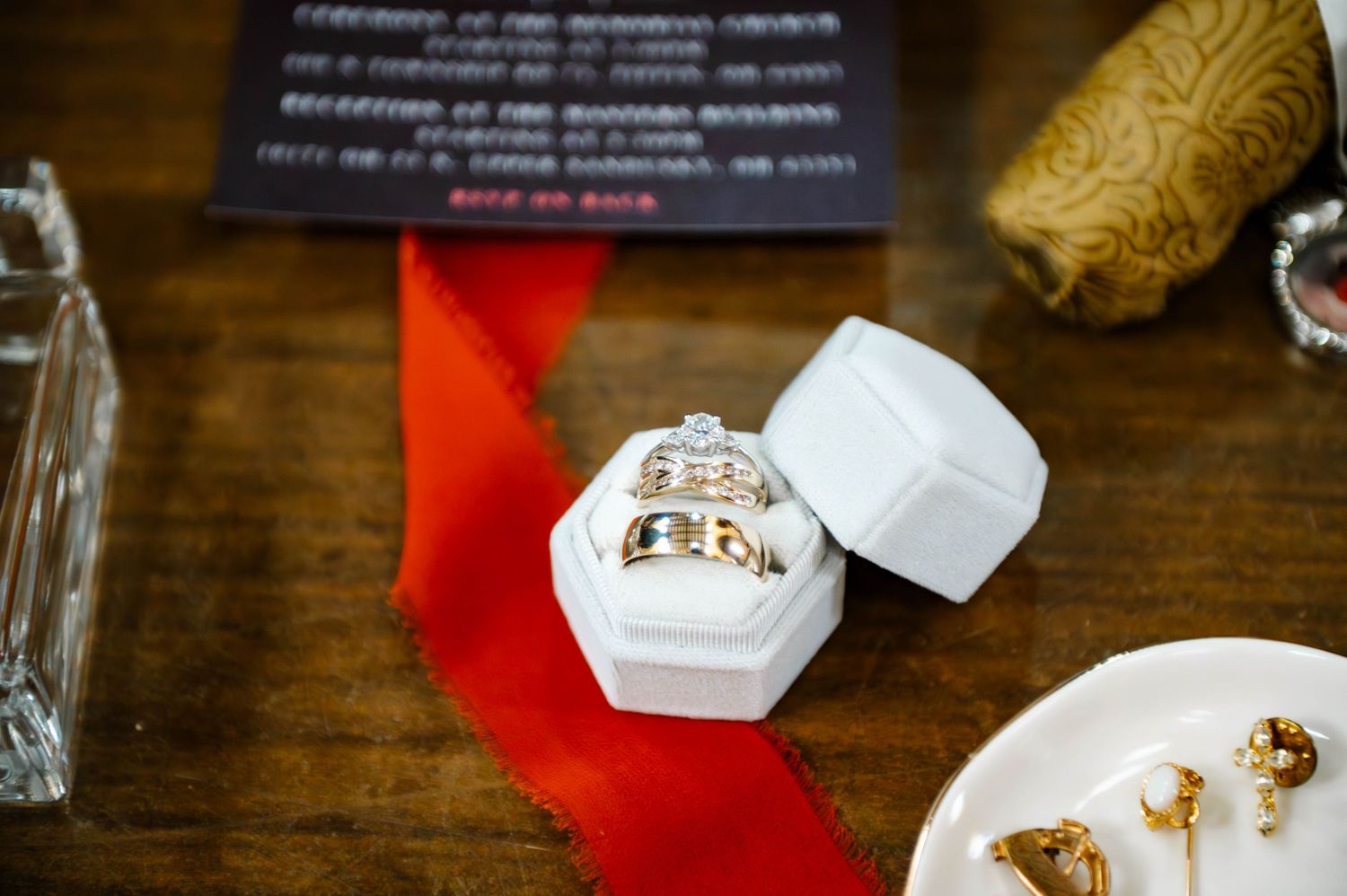 Wedding rings displayed in white hexagonal boxes on wooden surface.