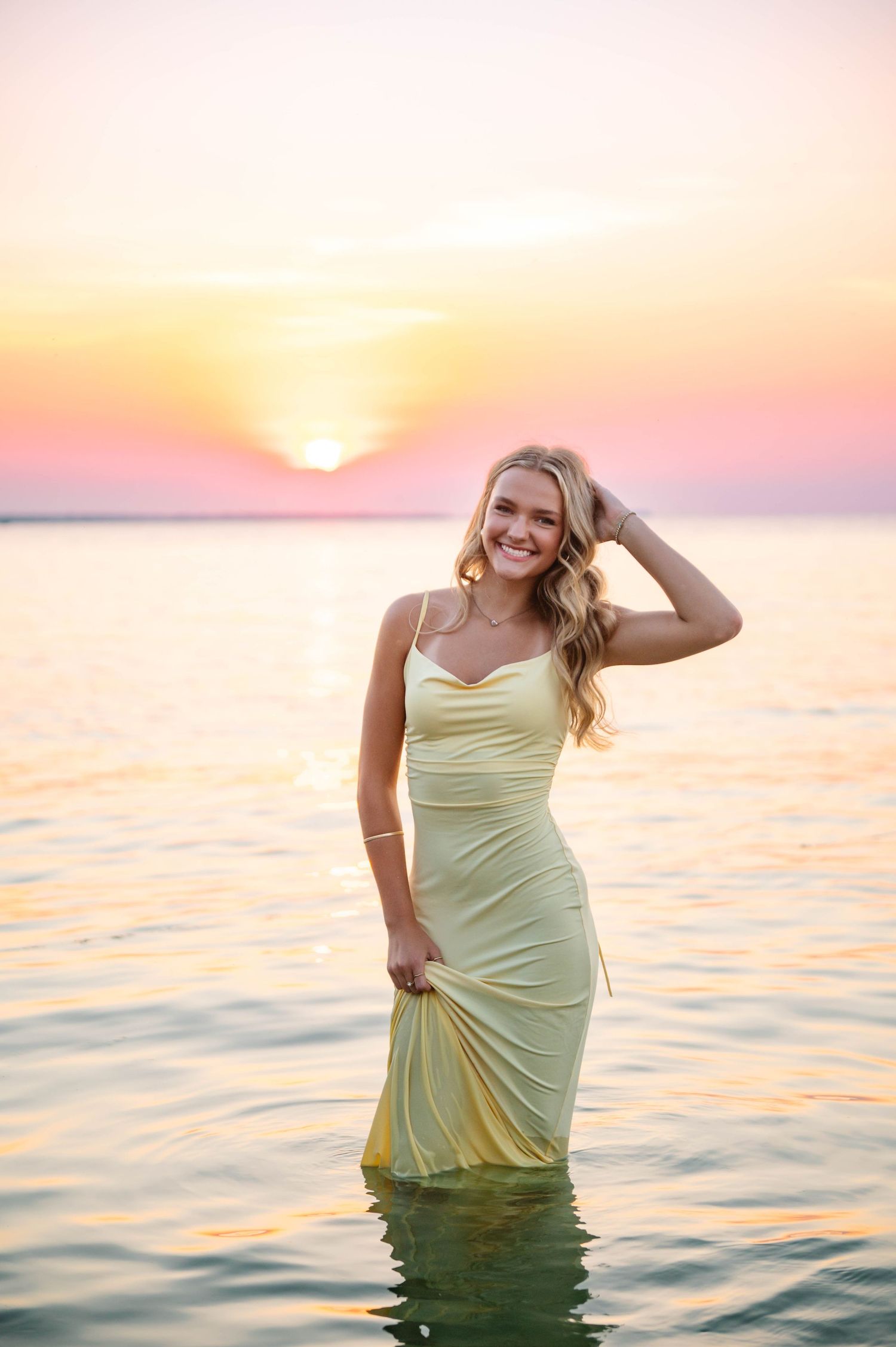 Joyful sunset photo session in the ocean with soft pink and yellow tones.