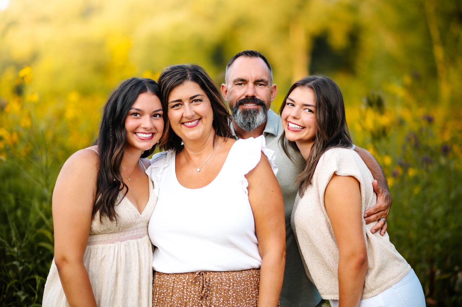 Friends gather for outdoor portraits in a sunlit meadow wearing coordinated neutral colors.