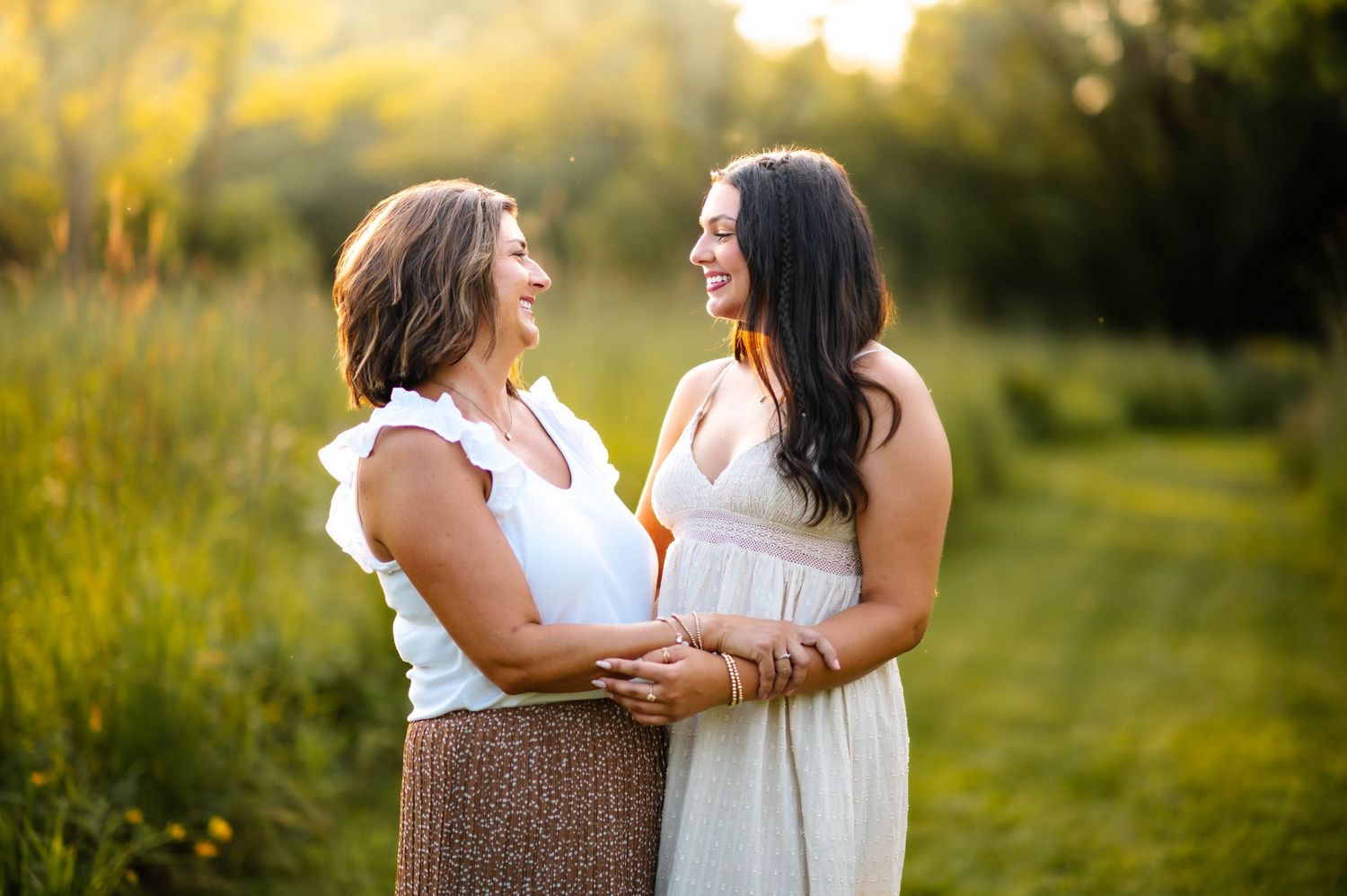 Two people share an intimate moment while standing in a golden field at sunset.