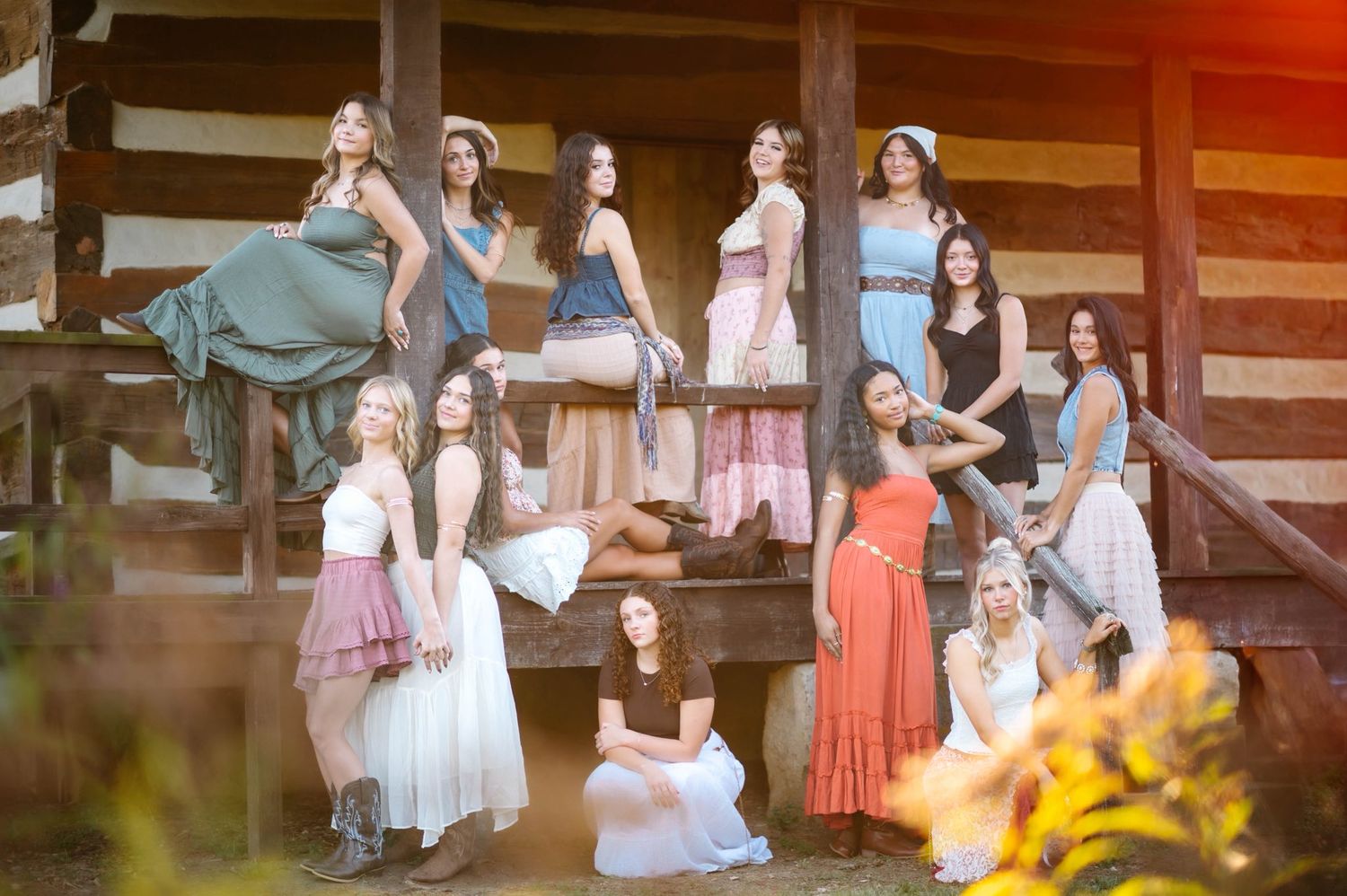 A group poses together under a rustic wooden structure at sunset.