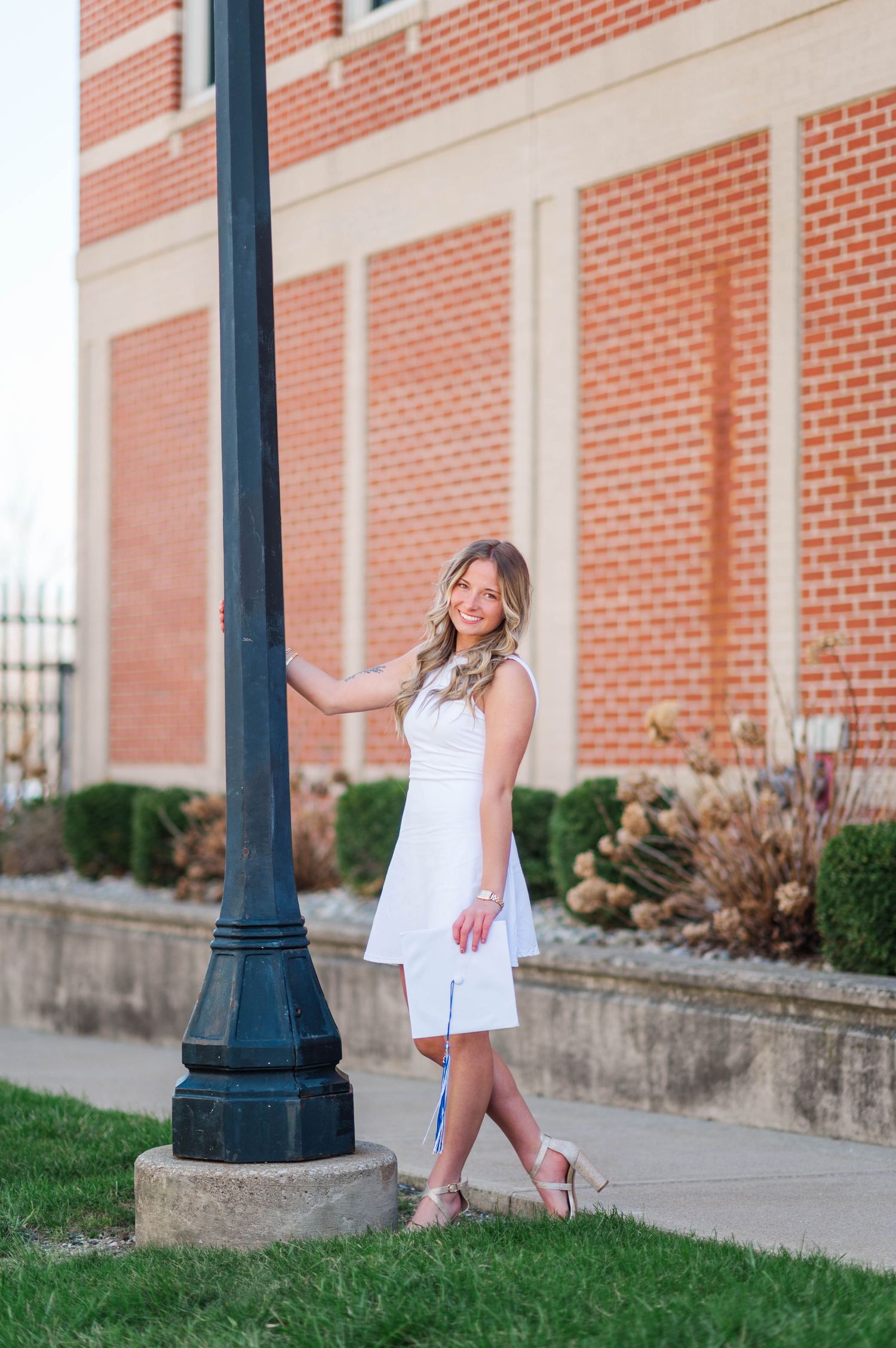 Elegant graduation portraits along brick building with classical architecture.